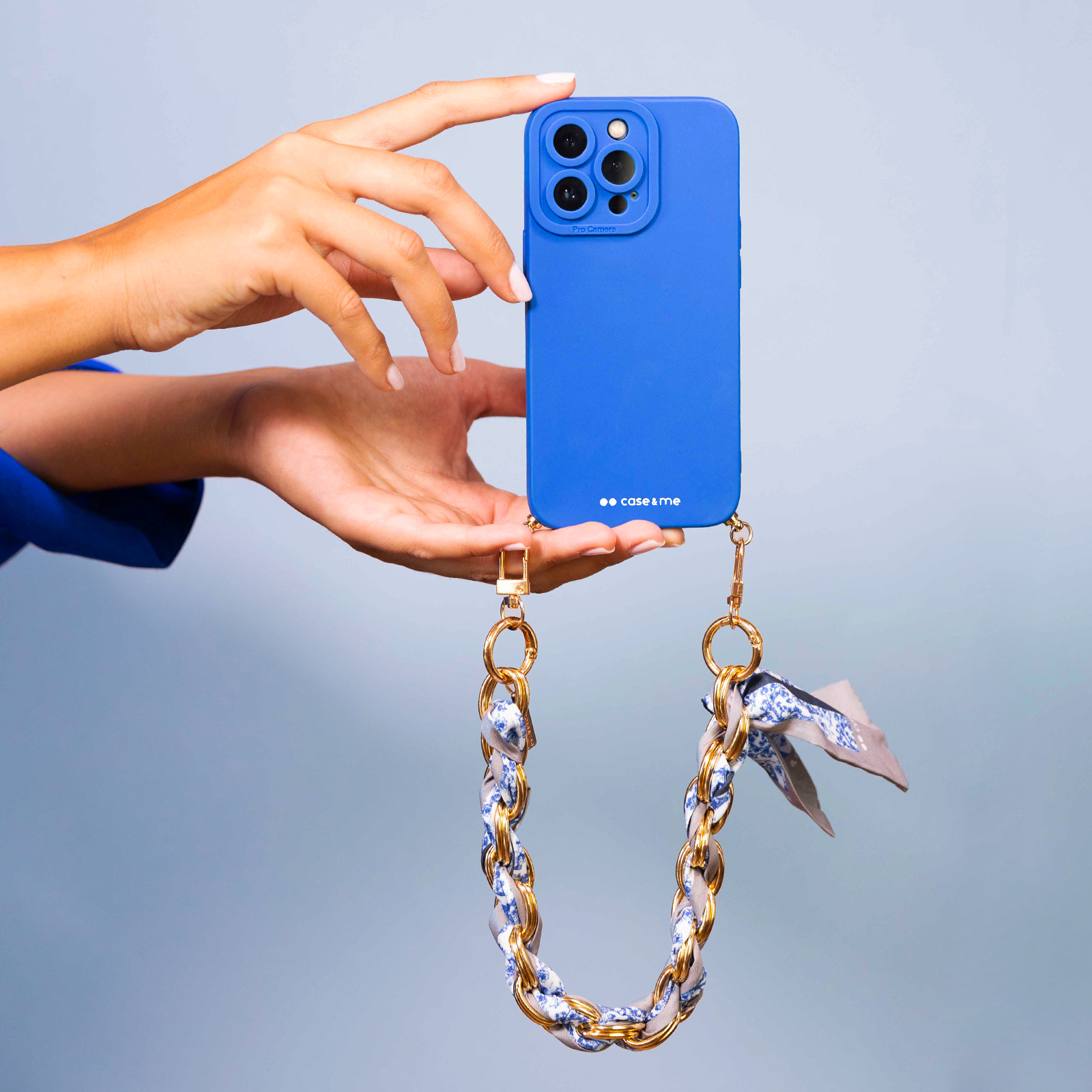 Custodia blu per telefono con sistema di fotocamere e catena dorata.