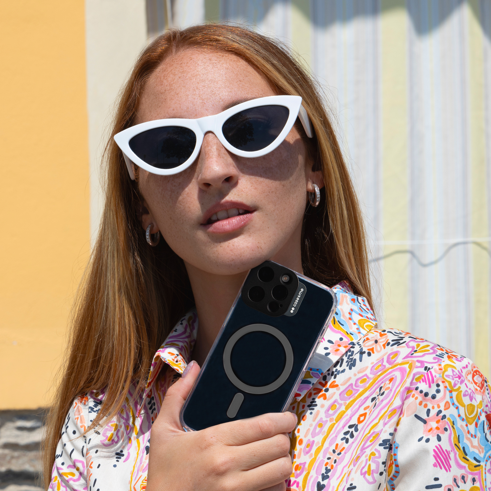 Mujer pelirroja con pecas sostiene un teléfono inteligente con funda.