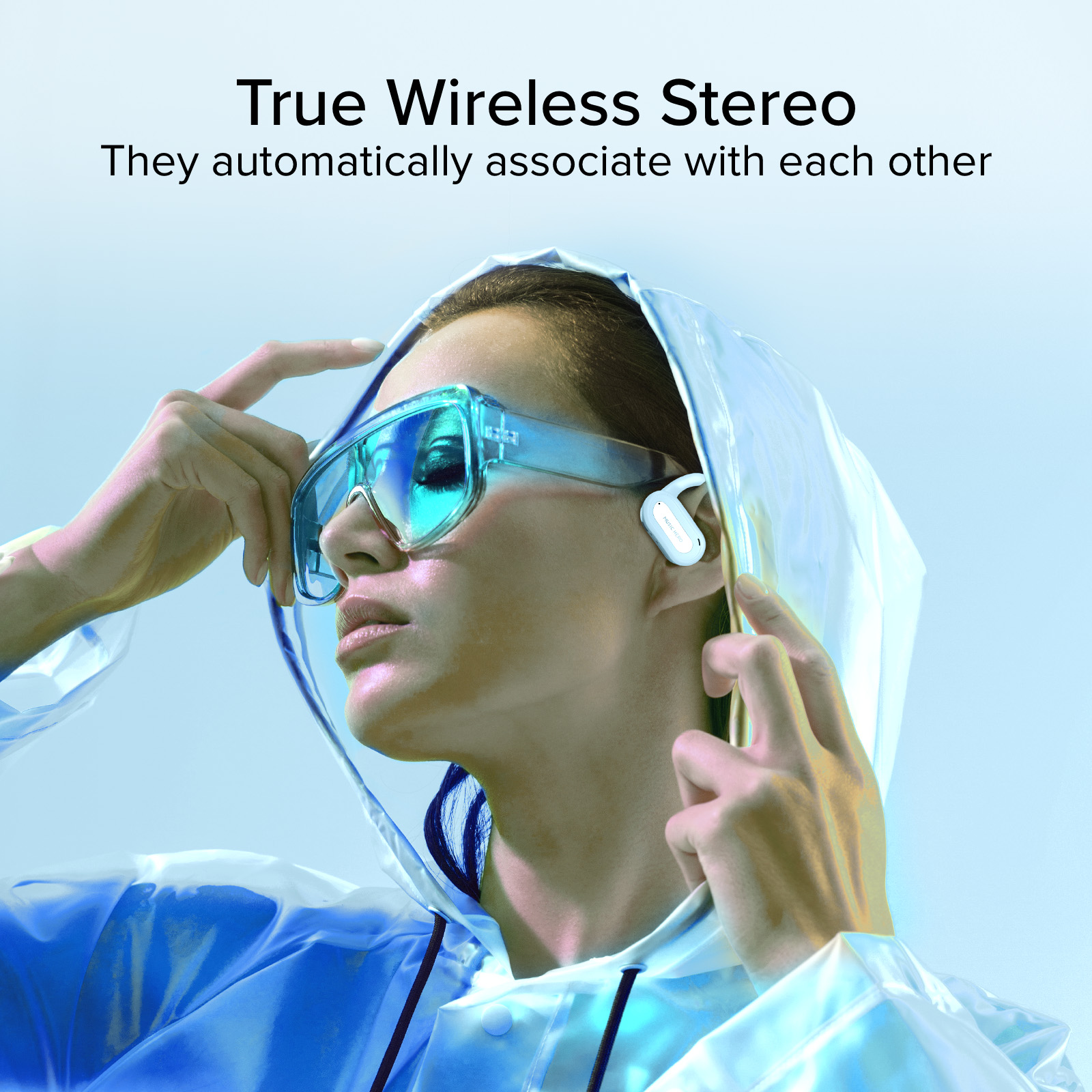 Mujer con gafas azules y auriculares, lleva un impermeable azul transparente.