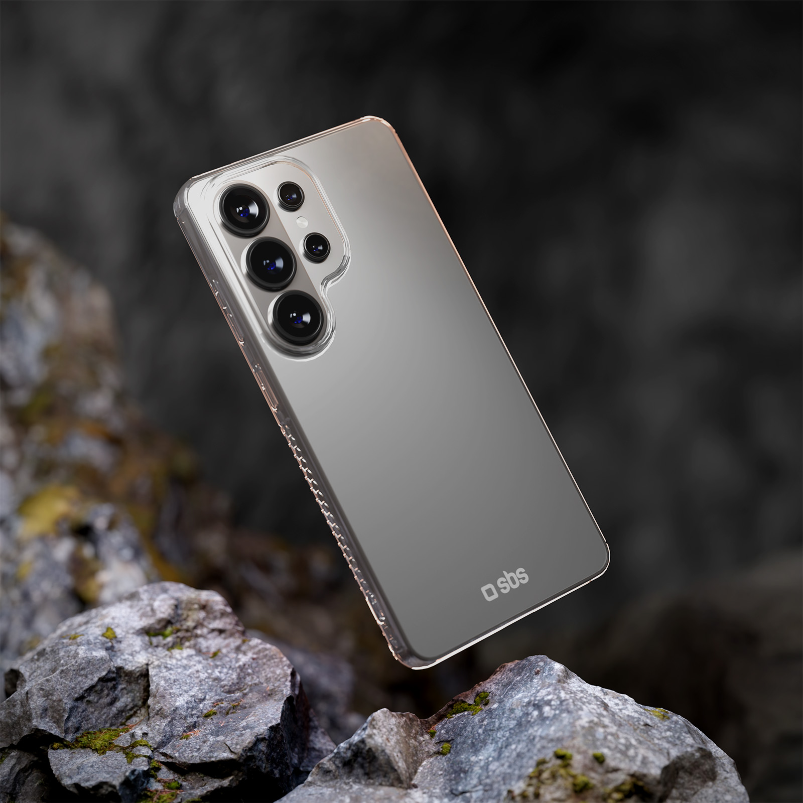 Un smartphone transparente con cuatro cámaras descansa sobre rocas.