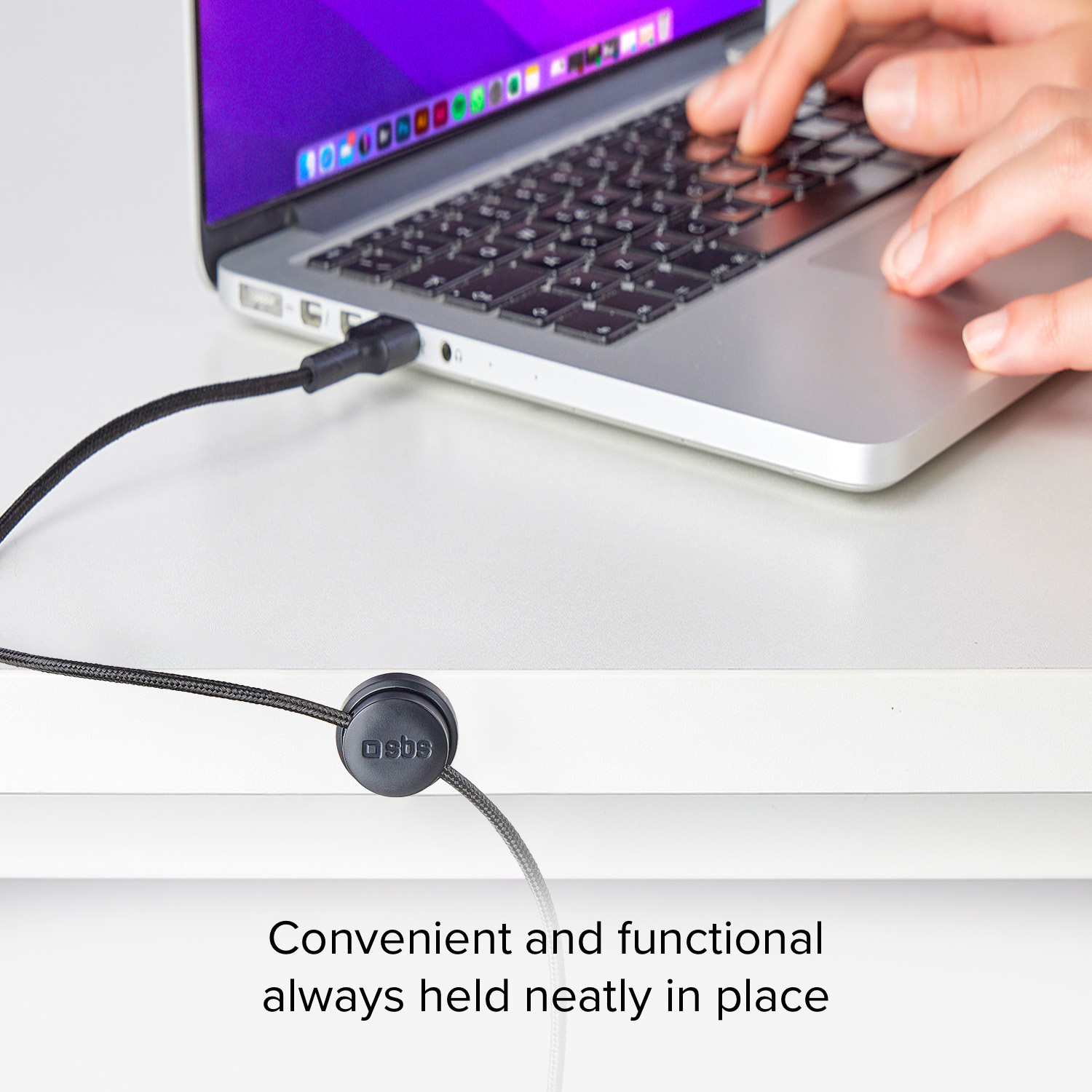 Hände tippen auf einem Laptop, der an ein Kabel angeschlossen ist, ein Kabelorganizer in der Nähe.