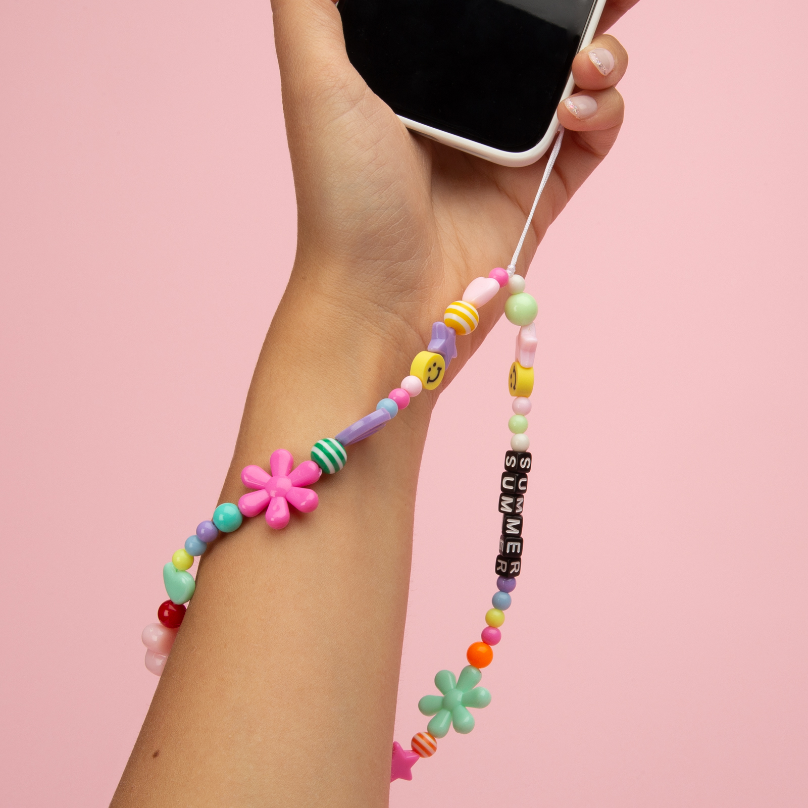 Mano che tiene il telefono con un cordino di perline colorato con scritto 'SUMMER'.