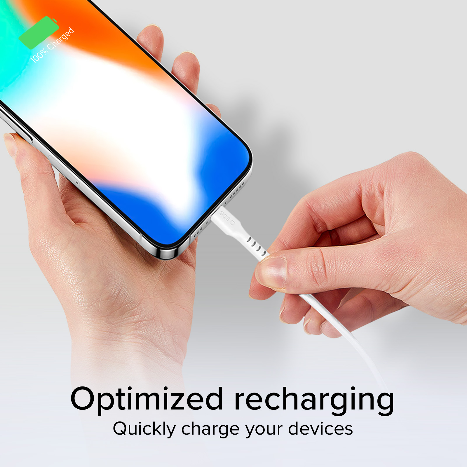 Une main branche un câble de chargement à un smartphone affichant 100 % de charge.