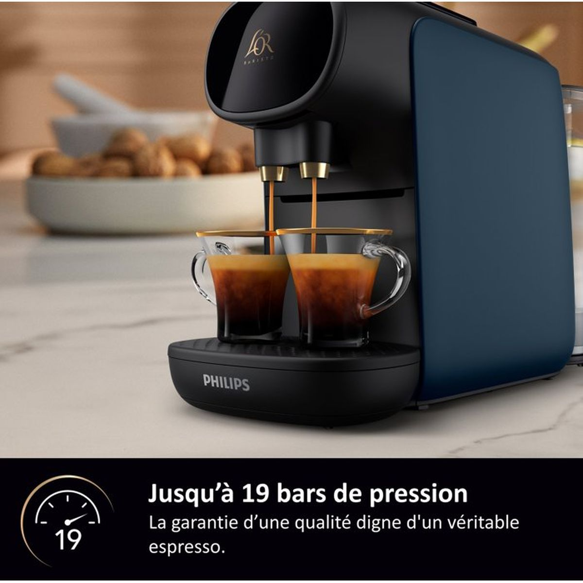 A coffee machine brews two espressos into glass cups. Blurred background.