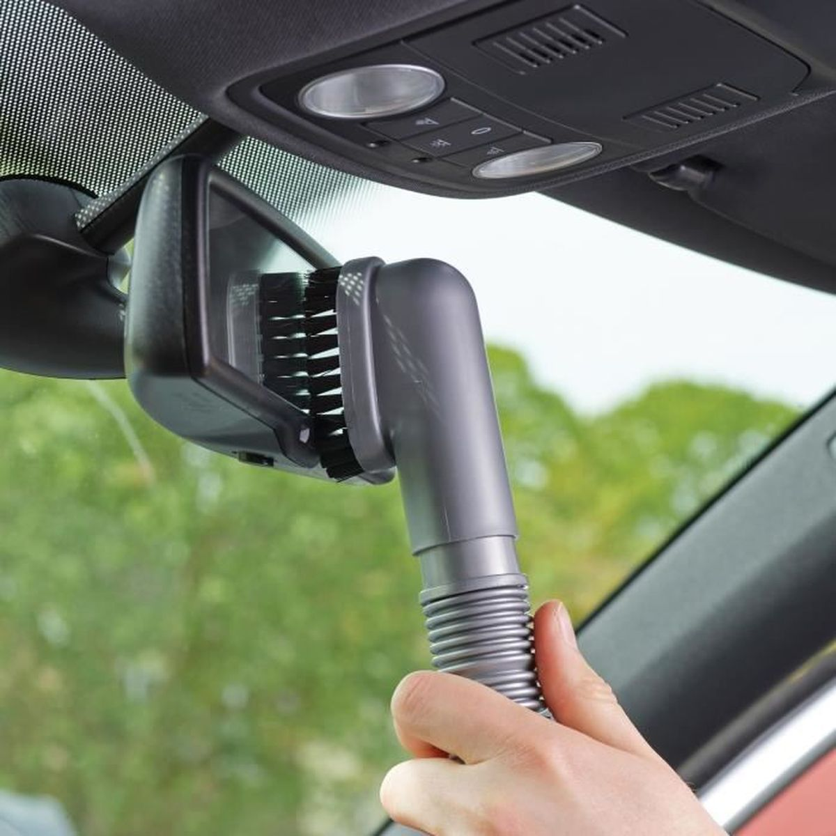 Ein Staubsaugeraufsatz mit Bürste wird an einem Rückspiegel im Auto befestigt.