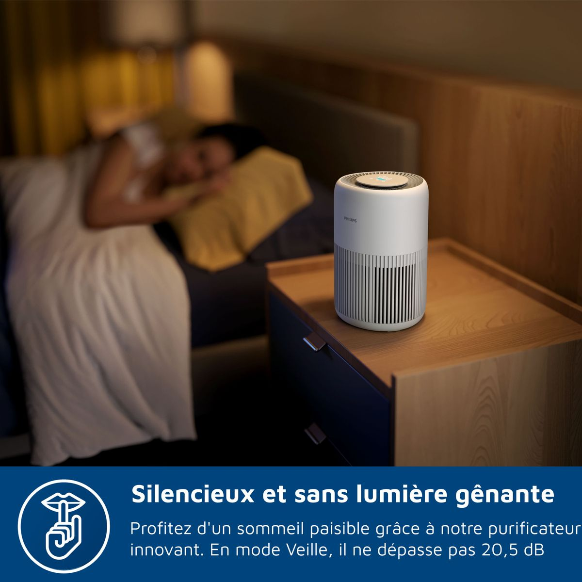 Un purificador de aire Philips blanco está en una mesita de noche junto a una persona durmiendo.