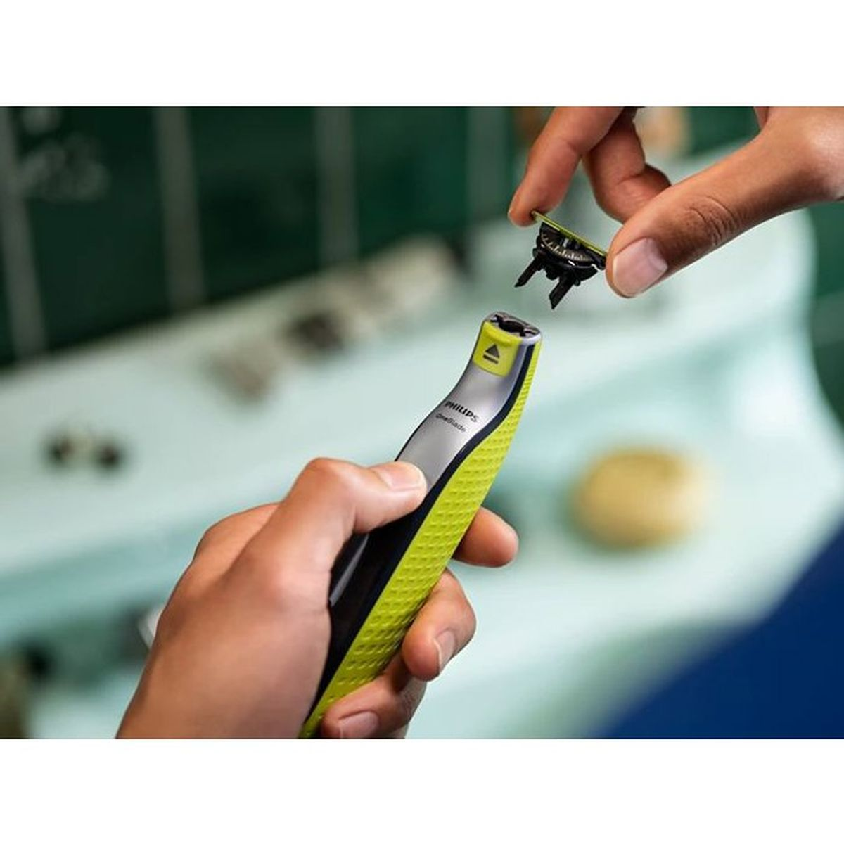 Una mano tiene un rifinitore Philips OneBlade verde mentre un'altra mano tiene la lama.