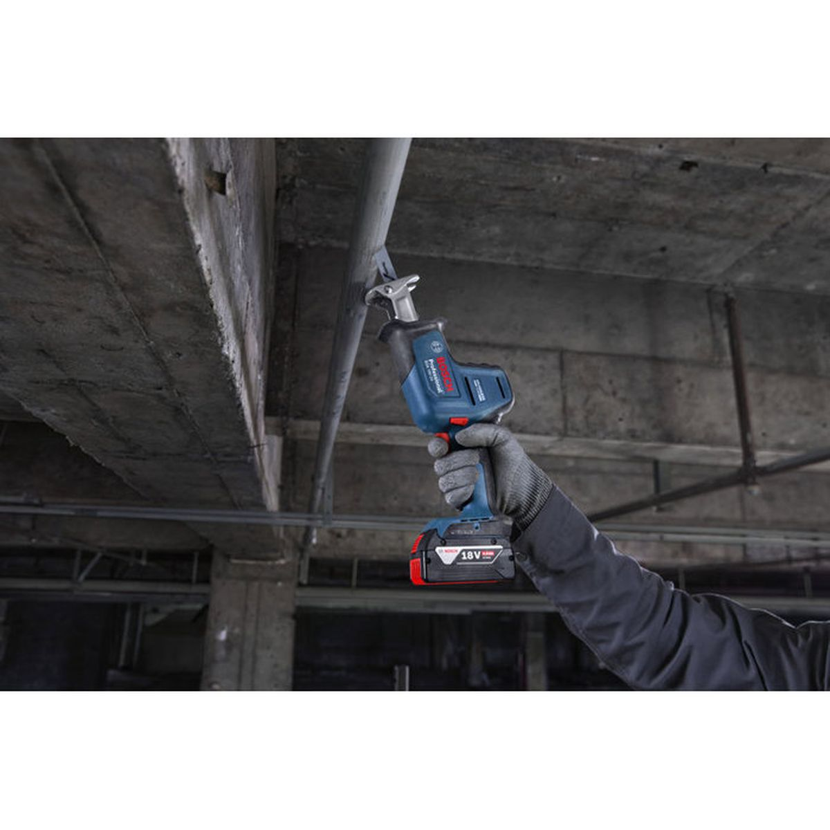 Ein Handwerker schneidet mit einem blauen Bosch Säbelsäge-Werkzeug ein Rohr.