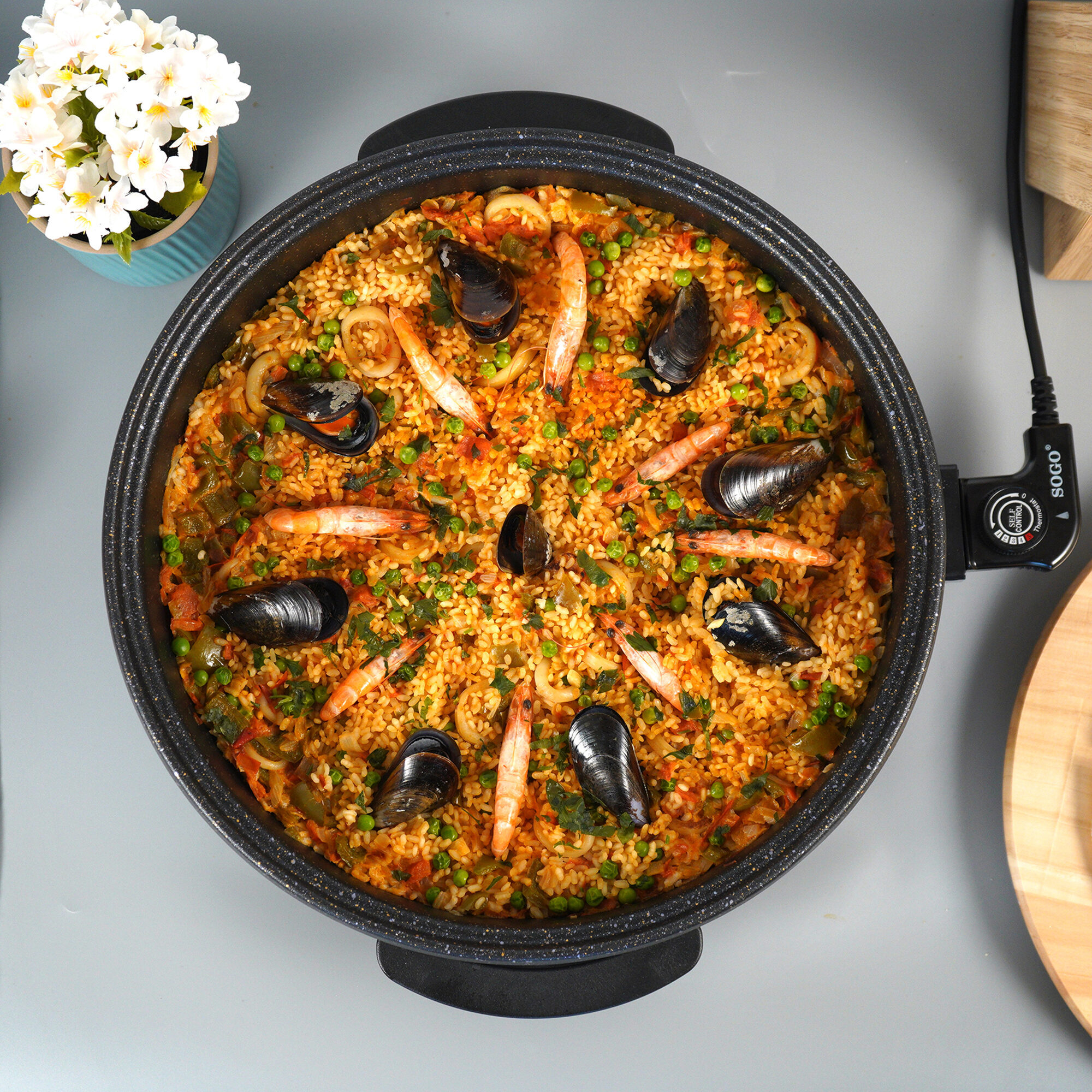Paella con gamberi e cozze in padella, guarnita con prezzemolo e piselli.