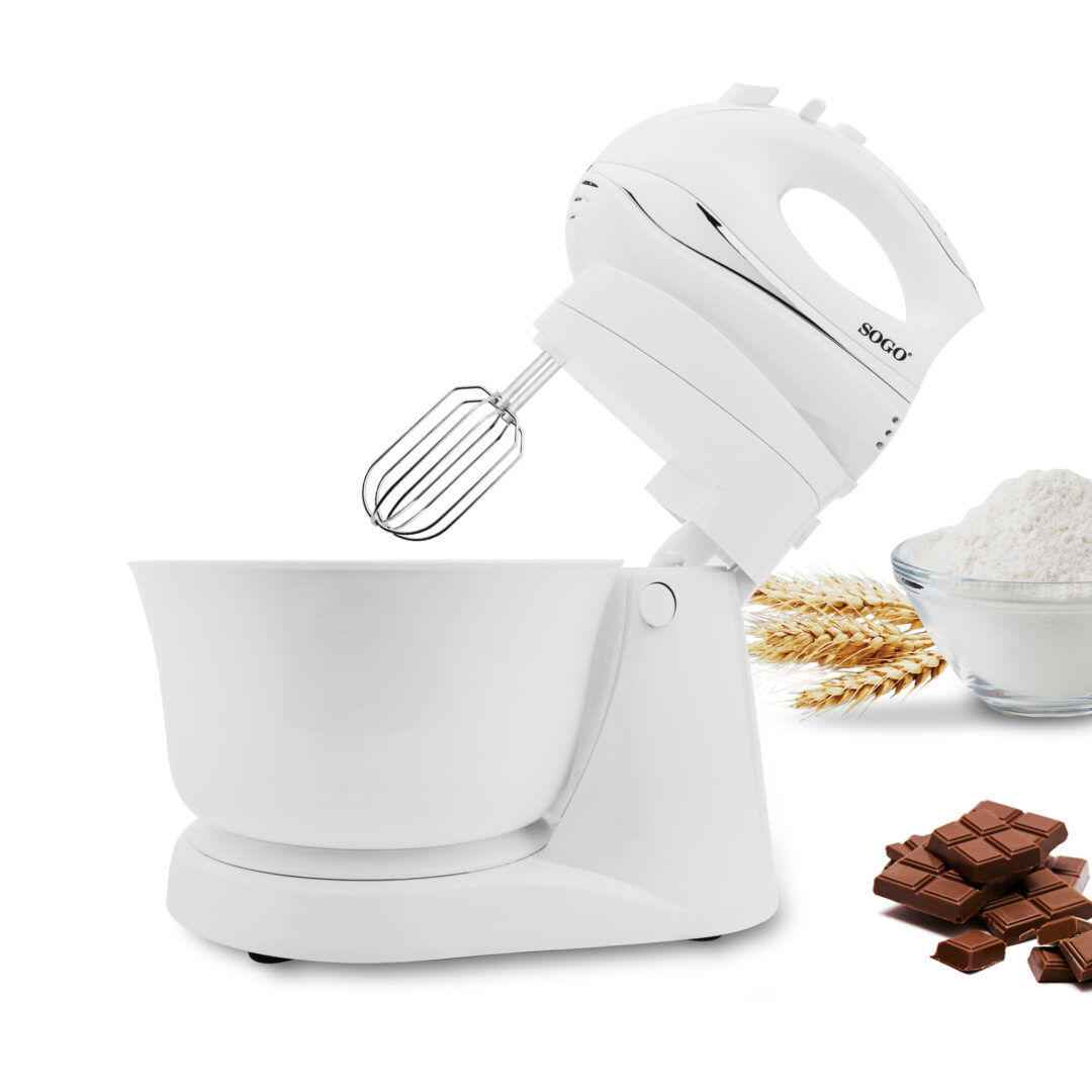 Un frullatore a mano bianco con ciotola, accanto a farina, spighe di grano e cioccolato.