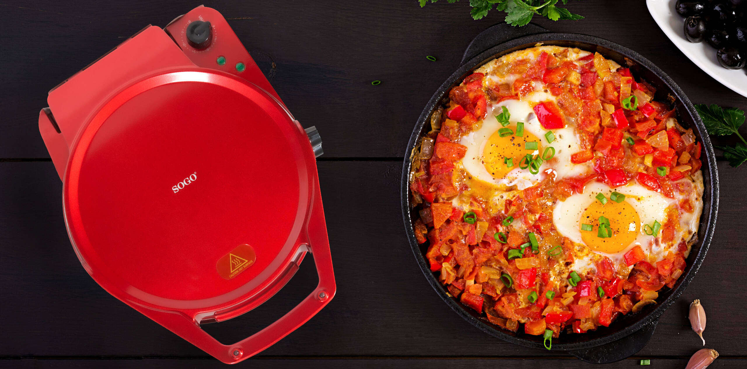 Grill rojo Sogo junto a sartén de shakshuka y aceitunas.