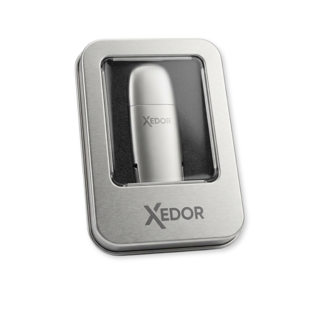 Une clé USB argentée avec le logo XEDOR dans une boîte en métal argenté.