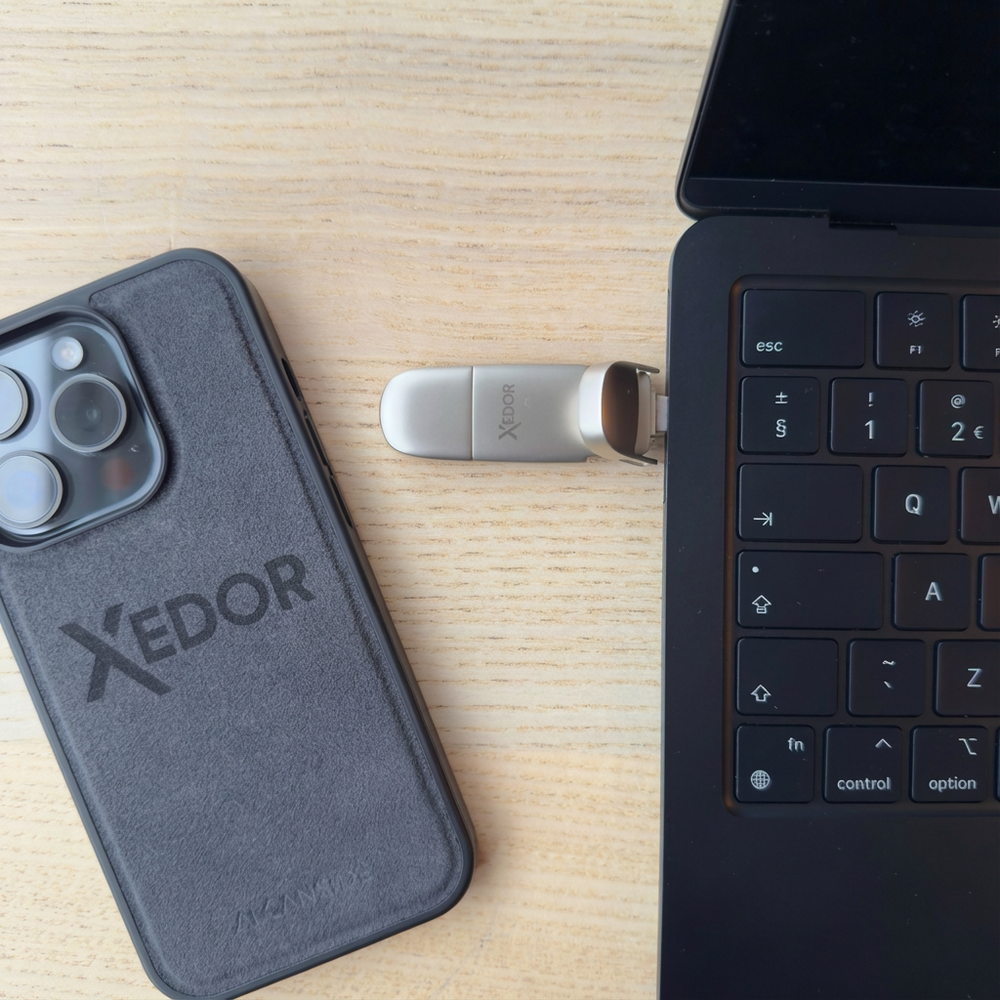 Une clé USB branchée sur un ordinateur portable à côté d'un iPhone avec étui.