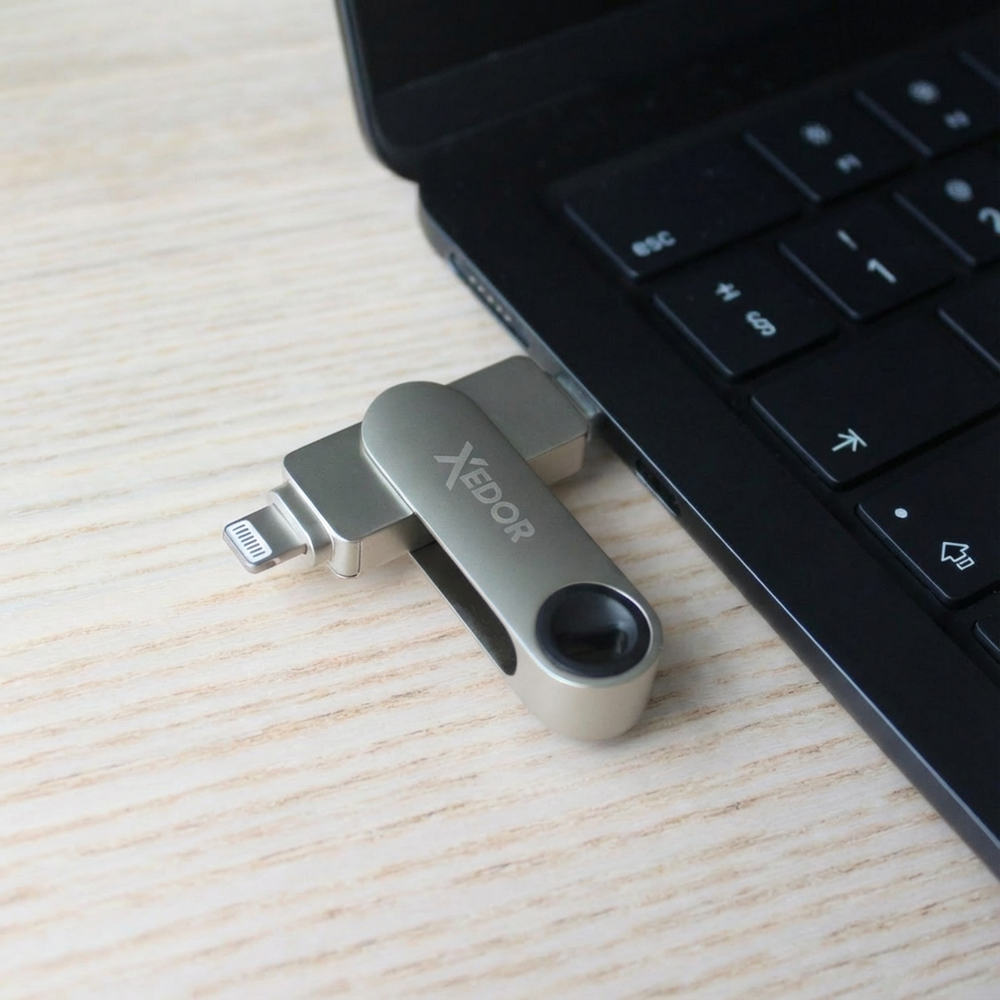 A silver USB drive with Lightning and USB-A connectors is plugged into a laptop.