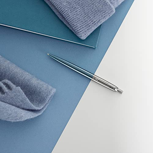 Ein blauer Stift liegt auf einem blauen Notizbuch und Stoff.