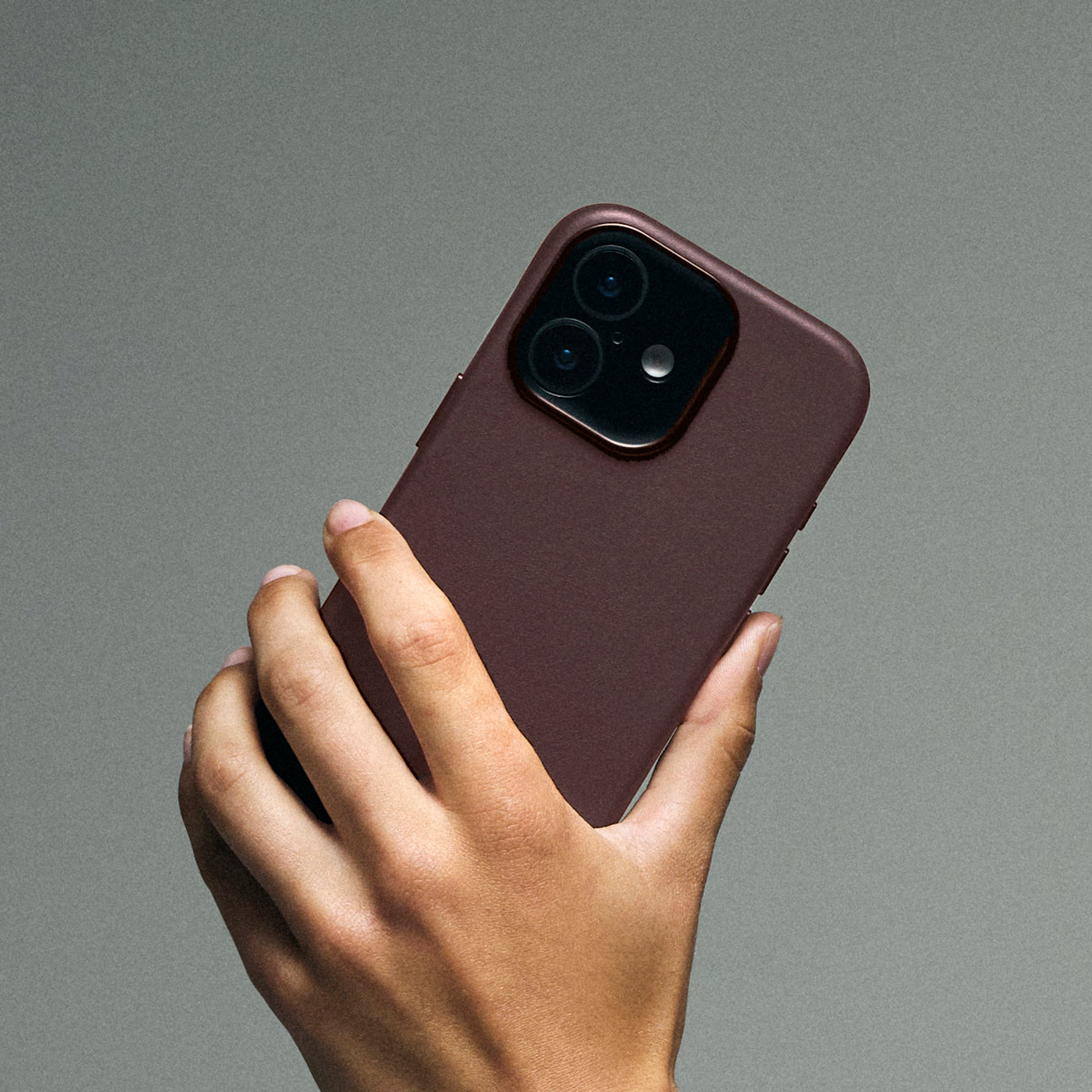Una mano tiene un telefono rosso scuro con due fotocamere.