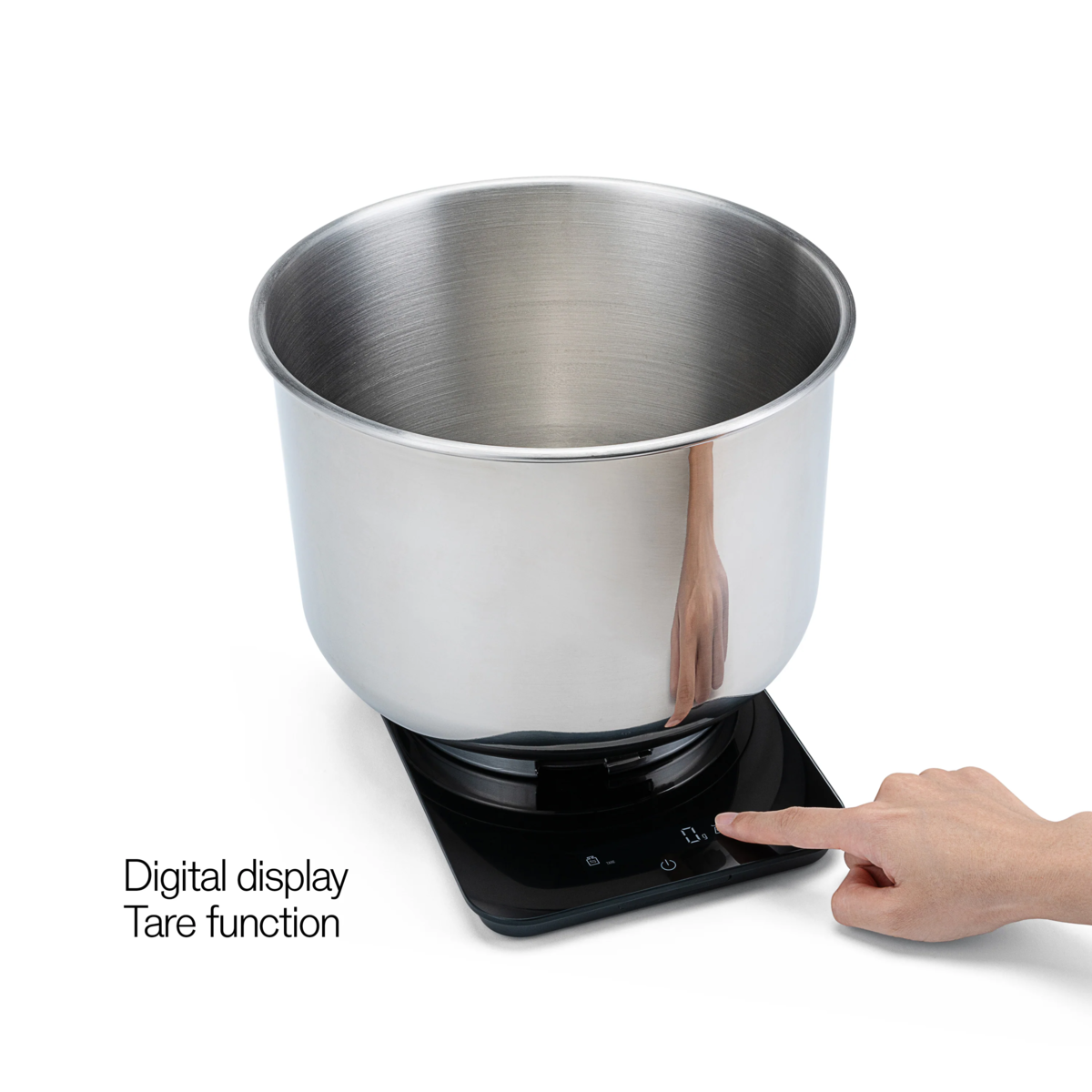 Edelstahlschüssel auf einer schwarzen Digitalwaage, eine Hand drückt auf die Tasten.
