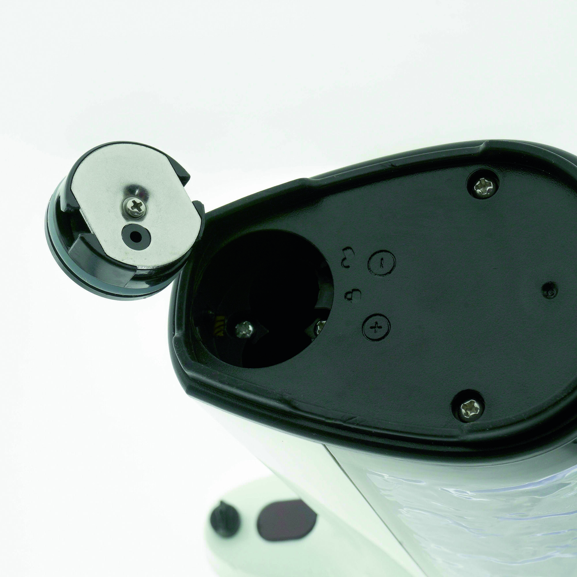 Coperchio vano batteria aperto mostra scomparti vuoti con viti su sfondo bianco.