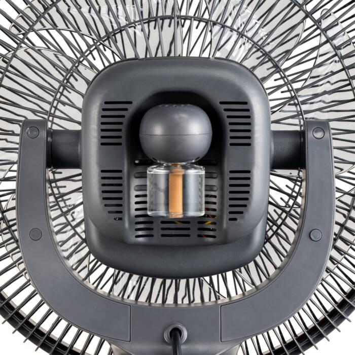 Primo piano del retro di un ventilatore nero, con motore e griglia in vista.