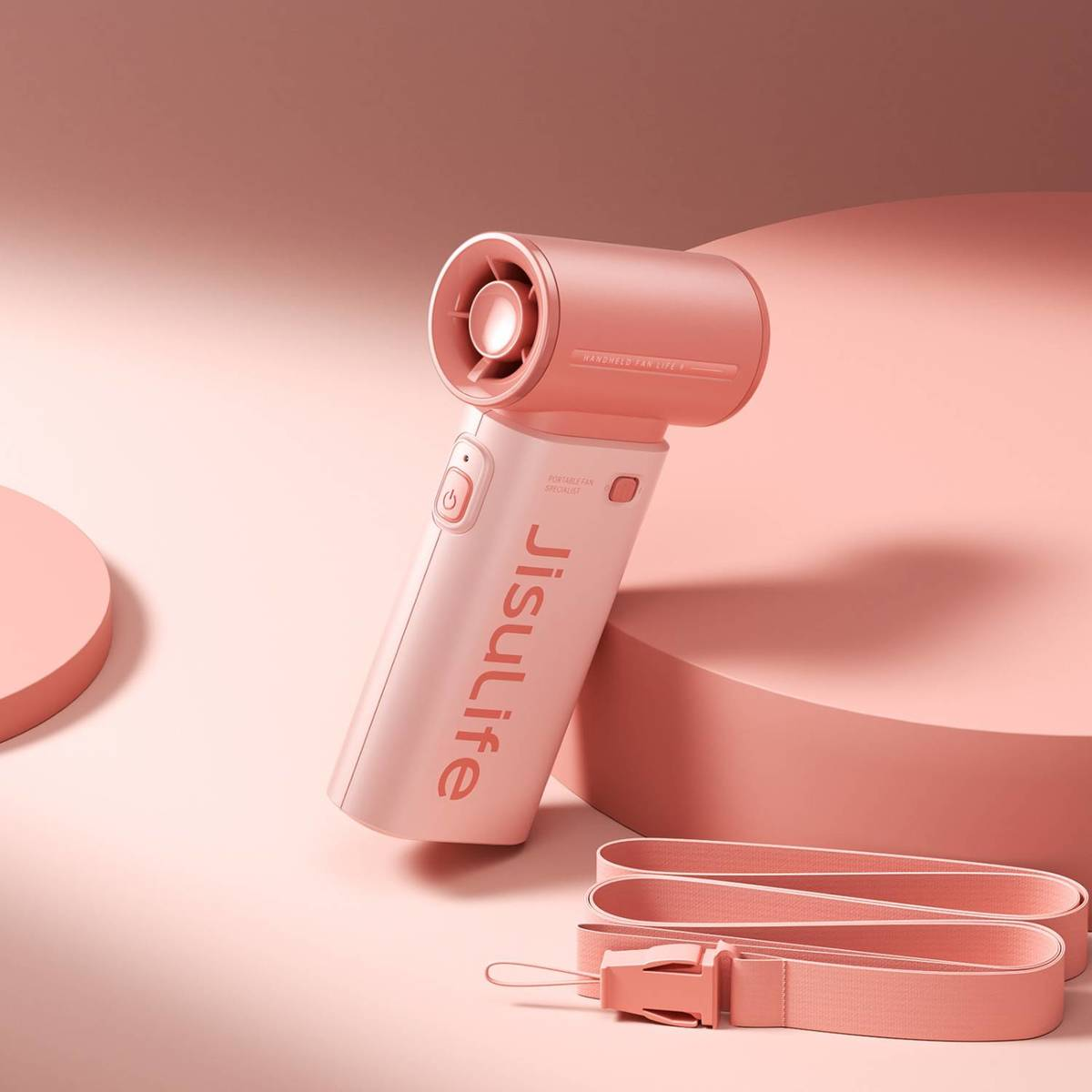 Un ventilatore portatile rosa con laccetto giace su un piedistallo rosa.