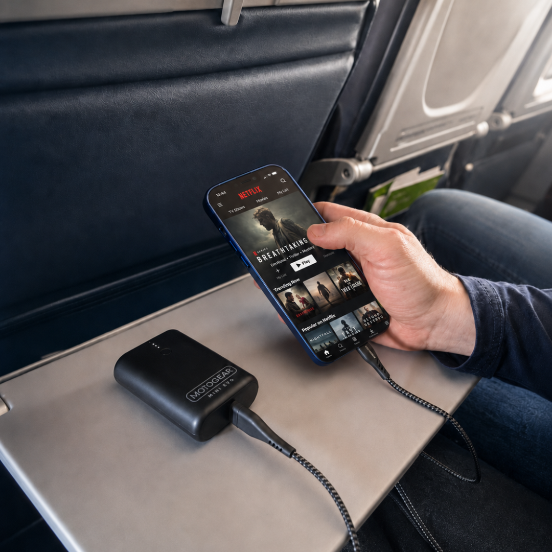 A person watches Netflix on a phone charging from a power bank while seated on an airplane.