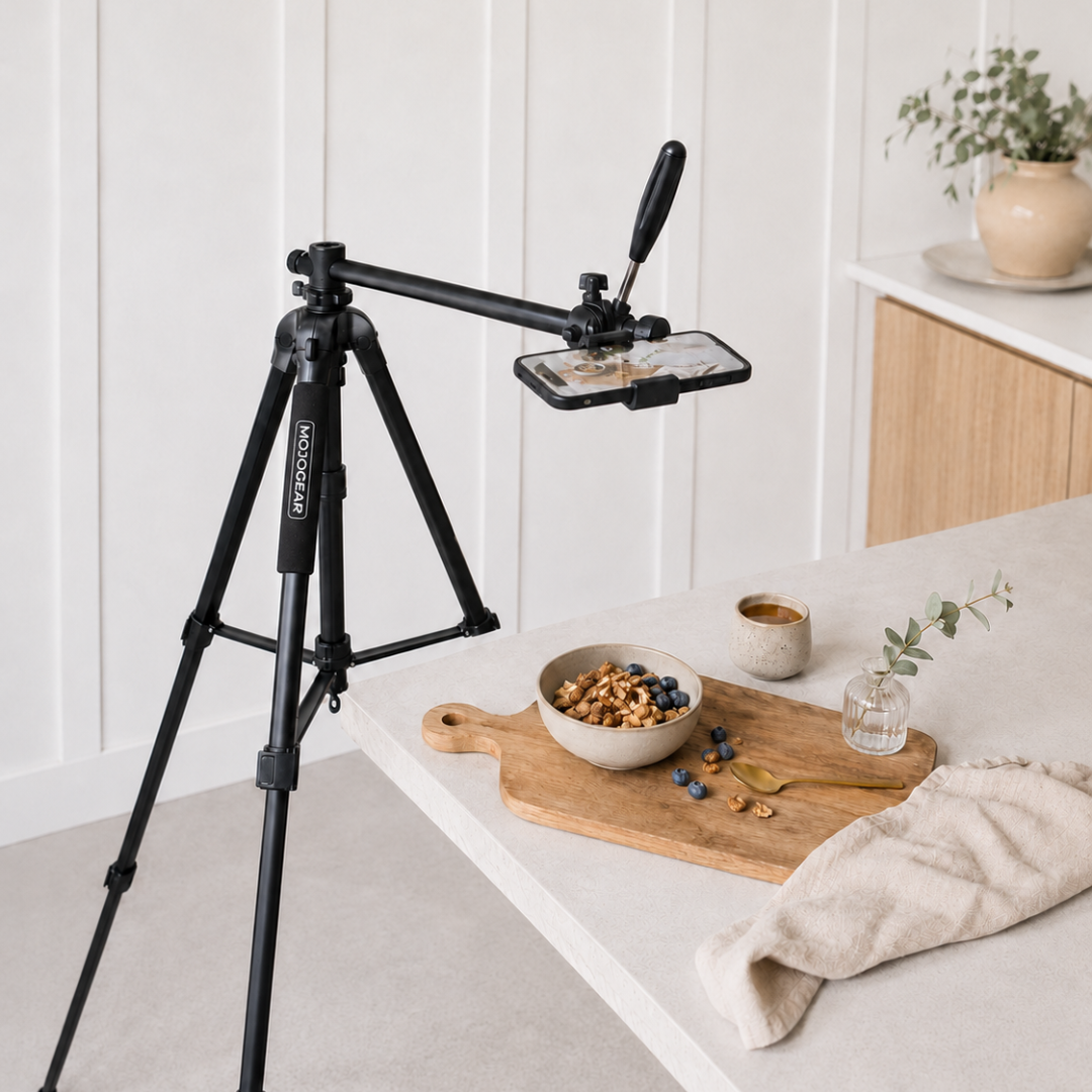 A tripod with a phone mount is set up near a kitchen counter with a bowl of cereal.