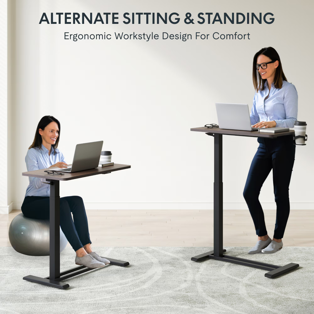 Femme assise sur ballon de gym, femme debout à un bureau réglable. Toutes deux travaillent sur portable.