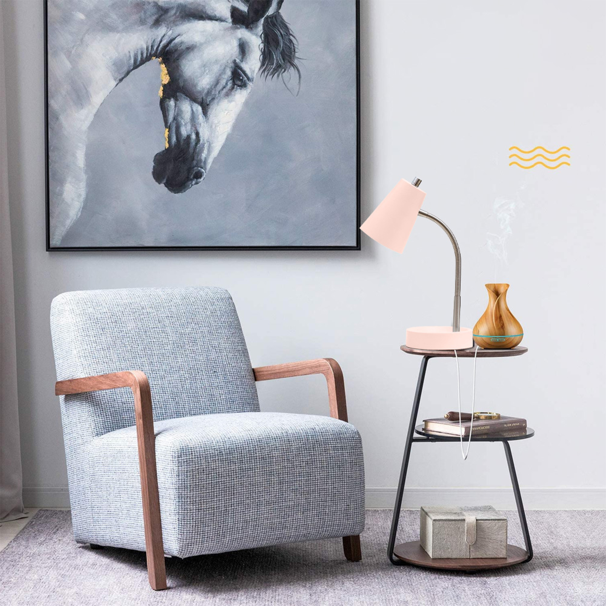 Ein grauer Sessel steht neben einem Beistelltisch mit Lampe, Diffusor und Büchern. Ein Pferdegemälde hängt an der Wand.