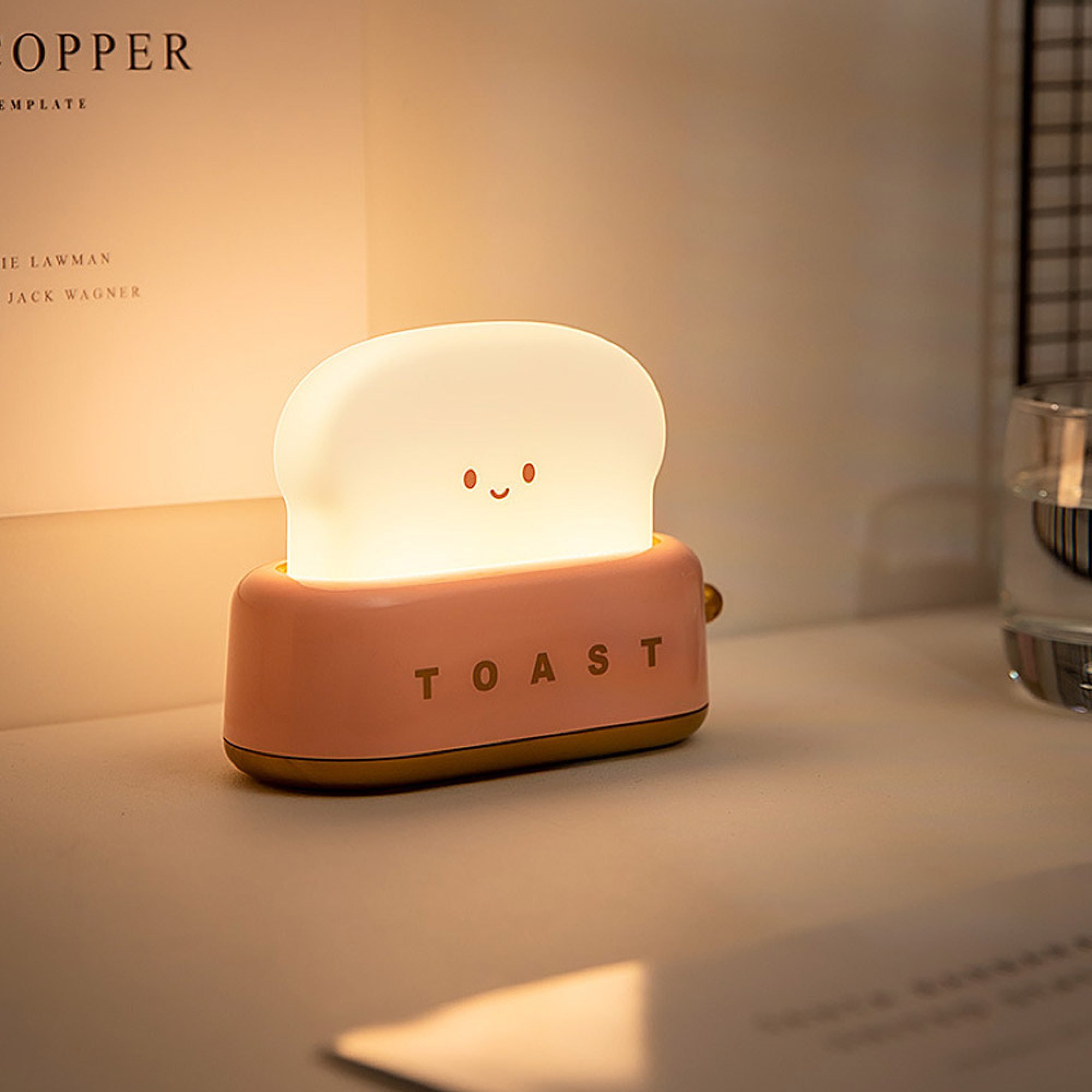 Ein rosa Toast-Nachtlicht mit einem süßen Gesicht leuchtet auf einem Schreibtisch.