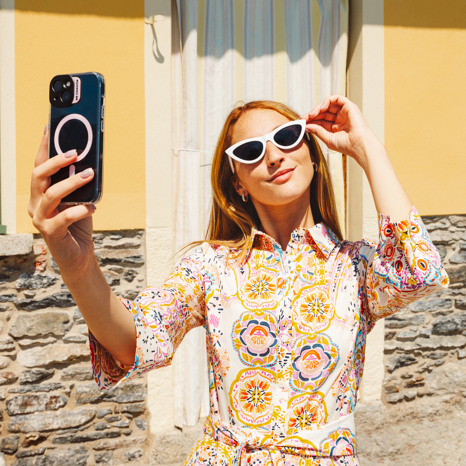Una mujer pelirroja se toma una selfie bajo el sol.