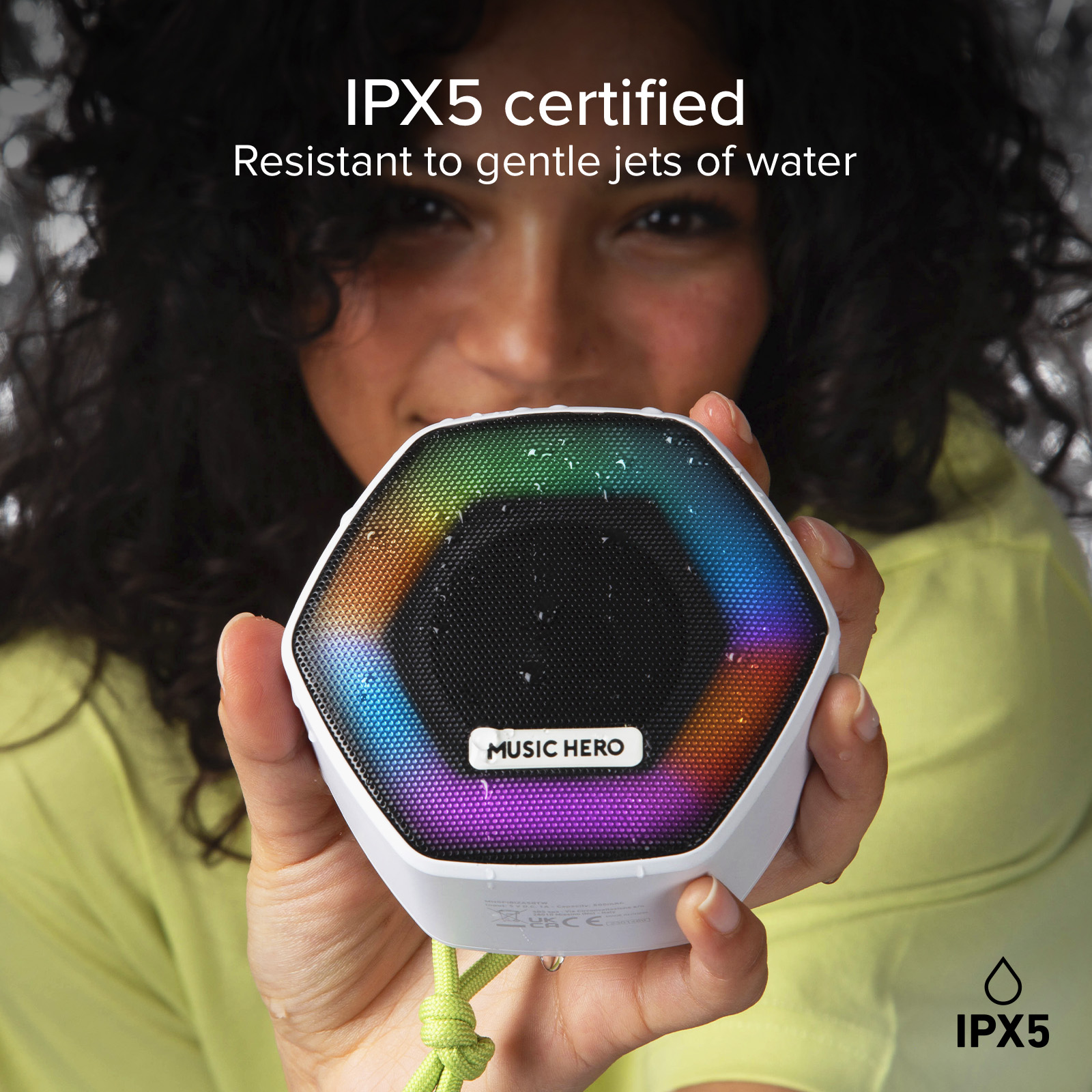Una donna tiene un altoparlante esagonale con illuminazione RGB e goccioline d'acqua.