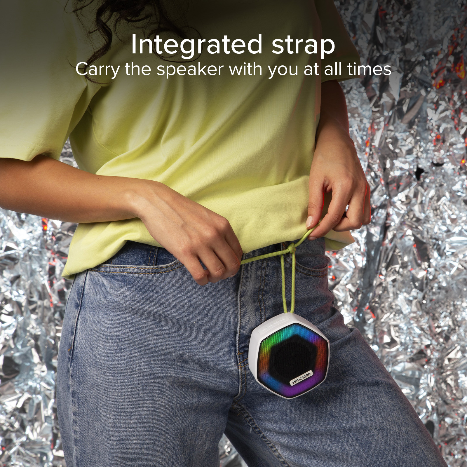 Una persona in jeans e top giallo tiene uno speaker bianco con effetti luminosi.
