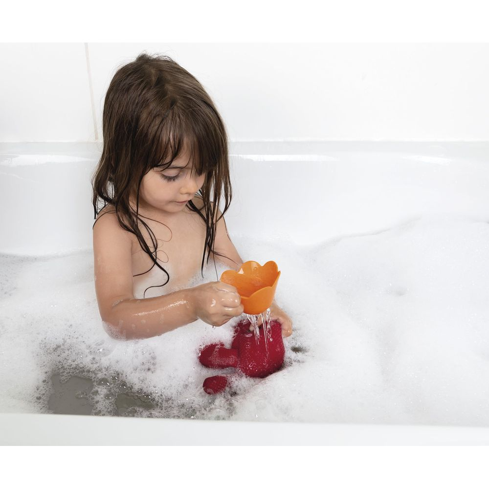 Ein kleines Mädchen spielt mit Spielzeug in der Badewanne voller Schaum.