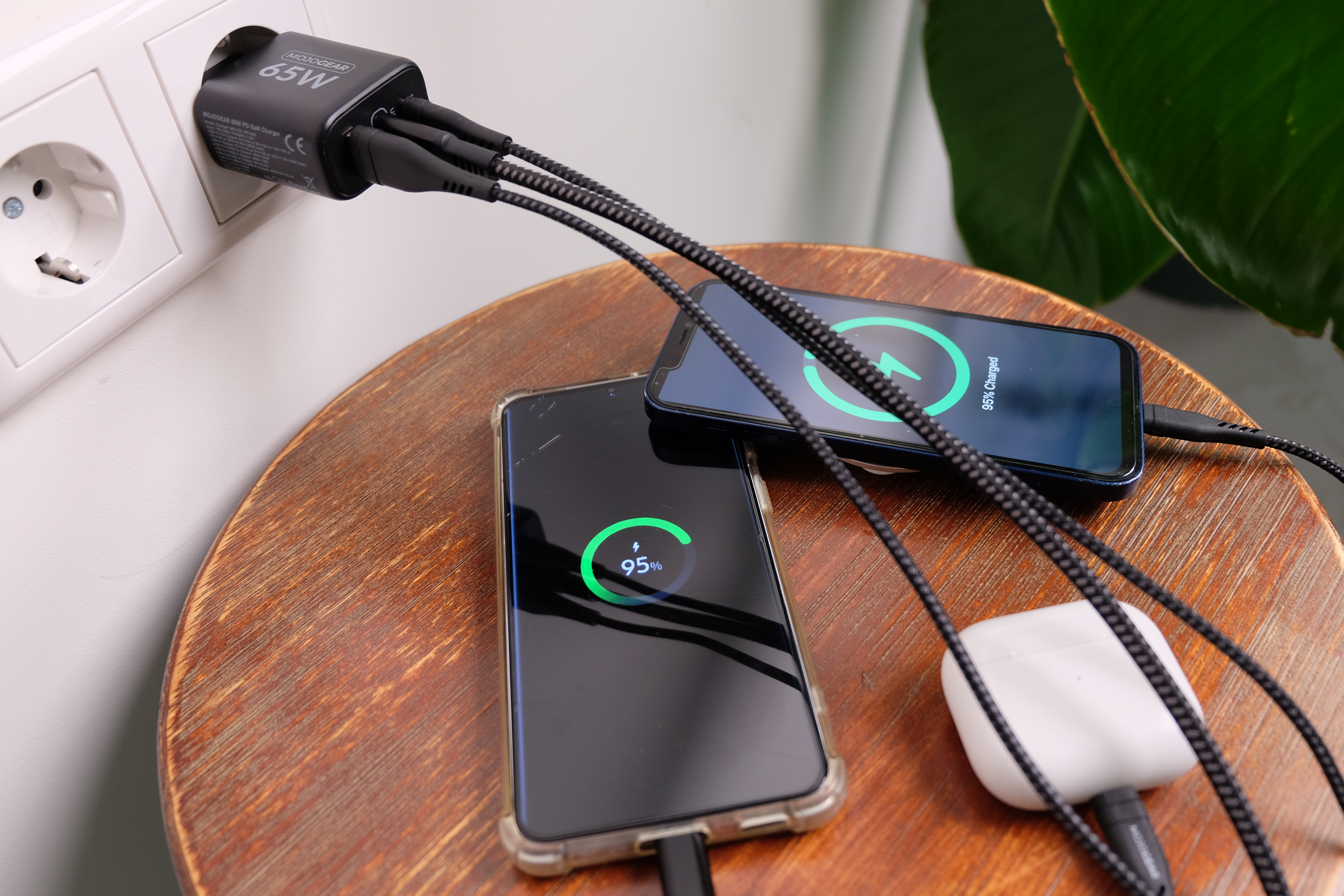 Ein 65W Ladegerät lädt zwei Handys und AirPods. Ein Handy zeigt 95% an.