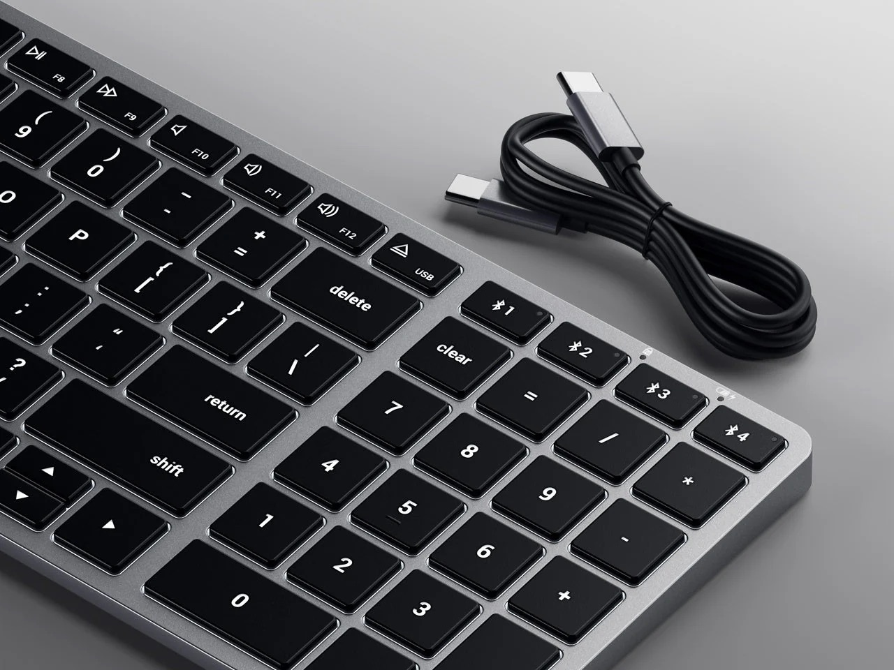 A silver keyboard with black keys and a black USB-C cable.