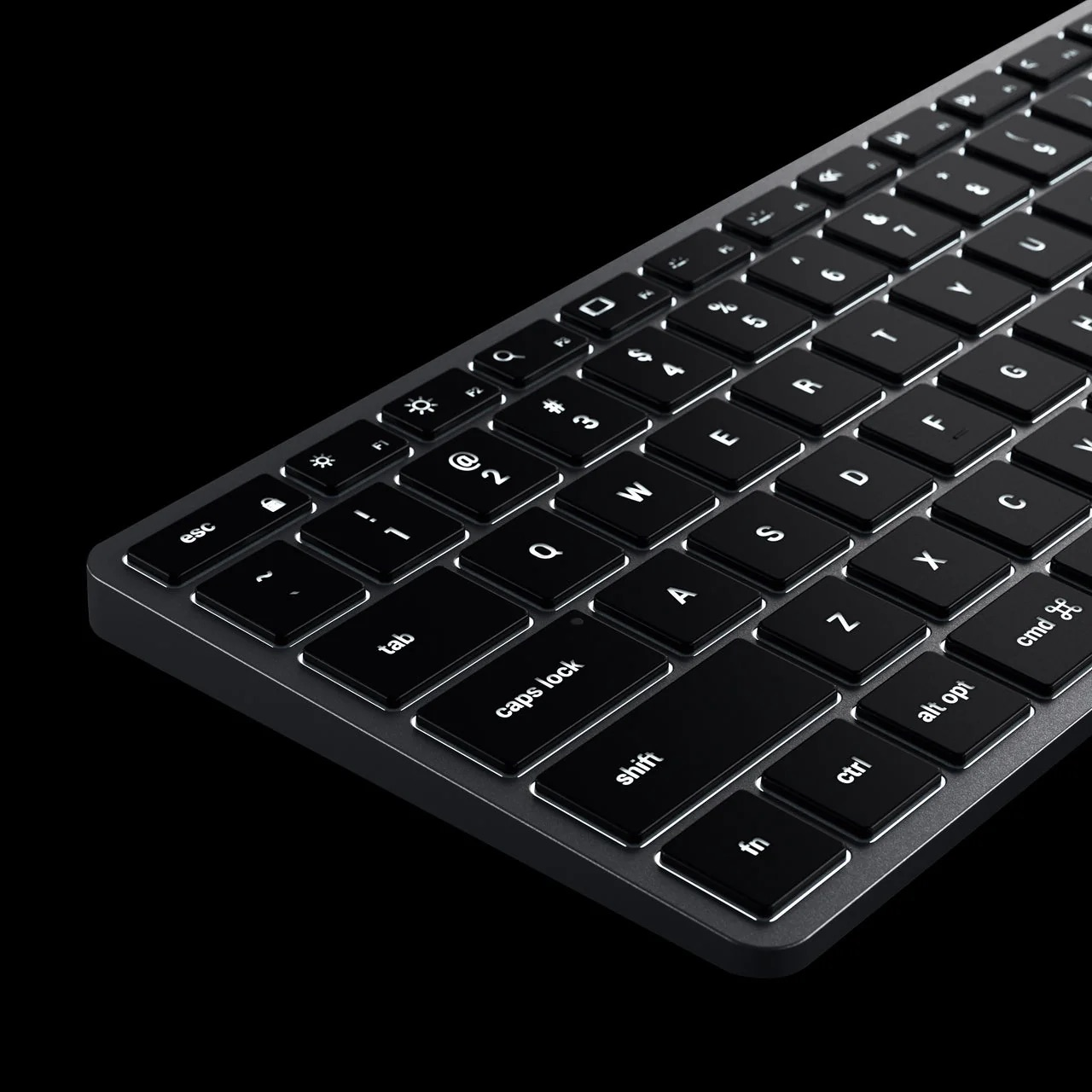 A close-up of a black keyboard with white backlit keys on a black background.