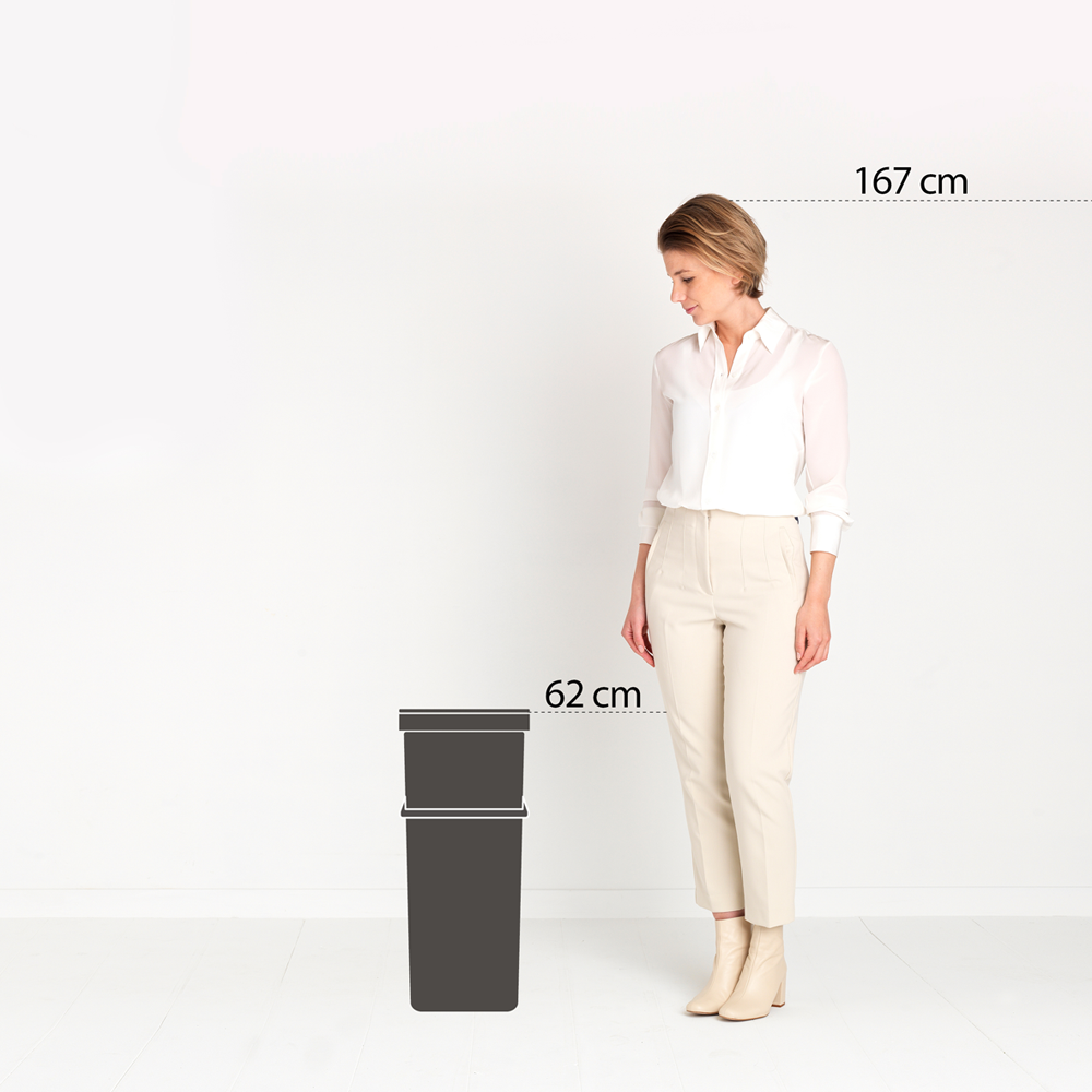 Une femme de 167 cm se tient à côté de deux conteneurs gris foncé.