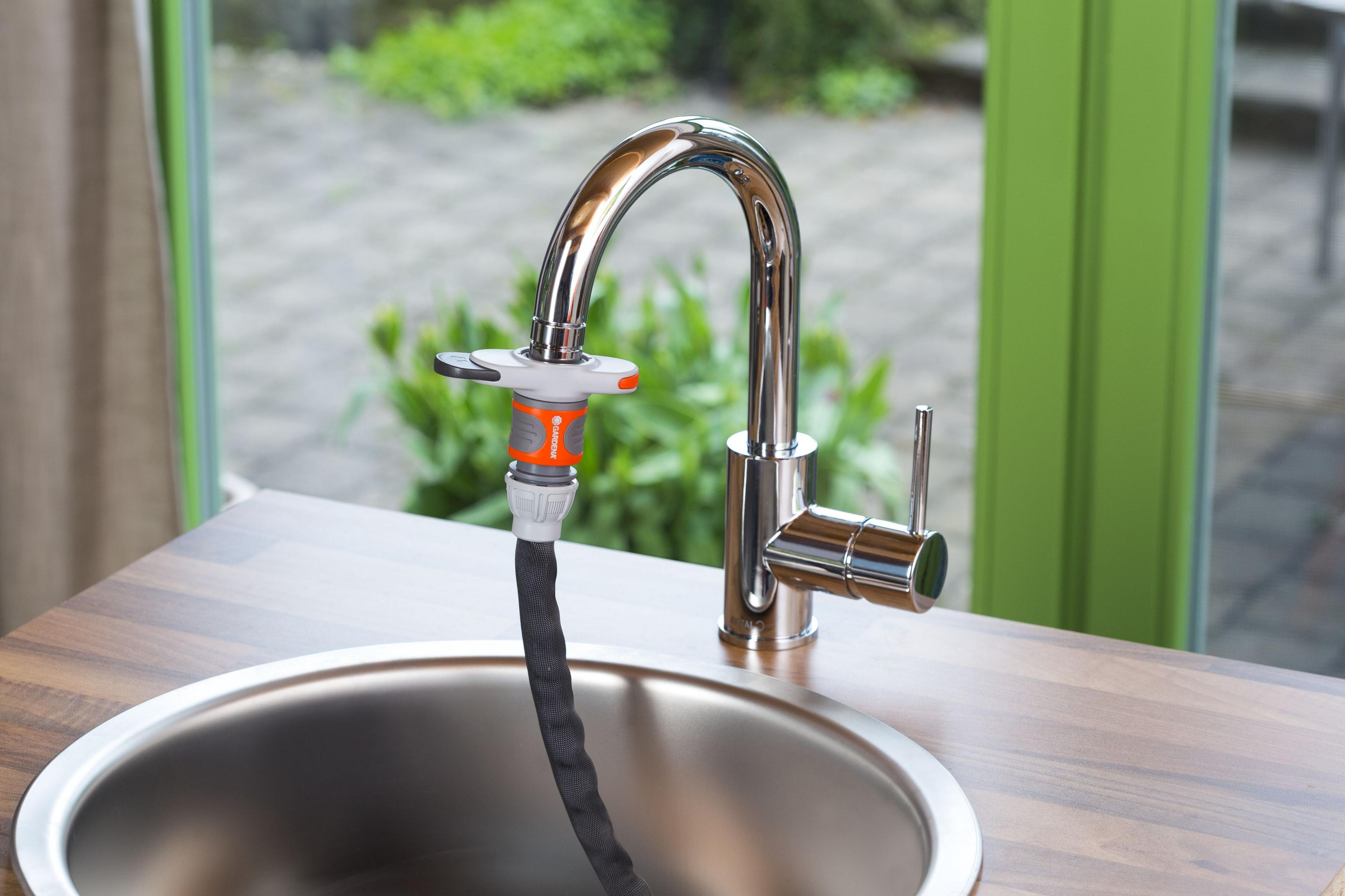 Ein Chromwasserhahn mit Schlauchanschluss über einem Spülbecken.