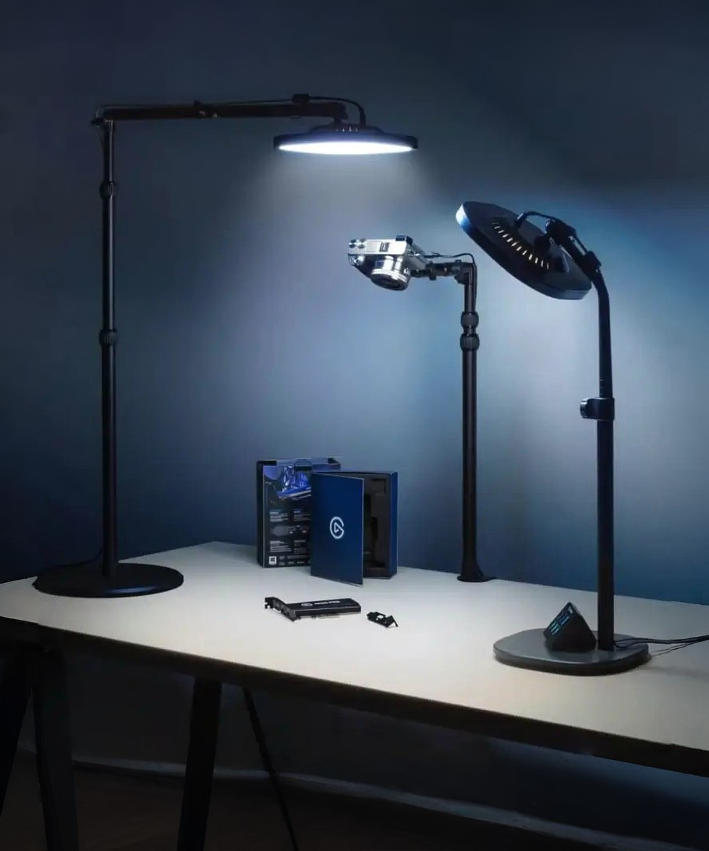 Drei Lampen, eine Kamera, eine Box und eine Karte auf einem Schreibtisch im Dunkeln.