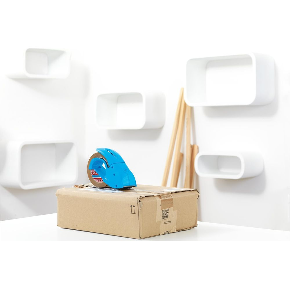 Ein Paket mit Klebebandabroller auf einem Tisch, weiße Regale im Hintergrund.
