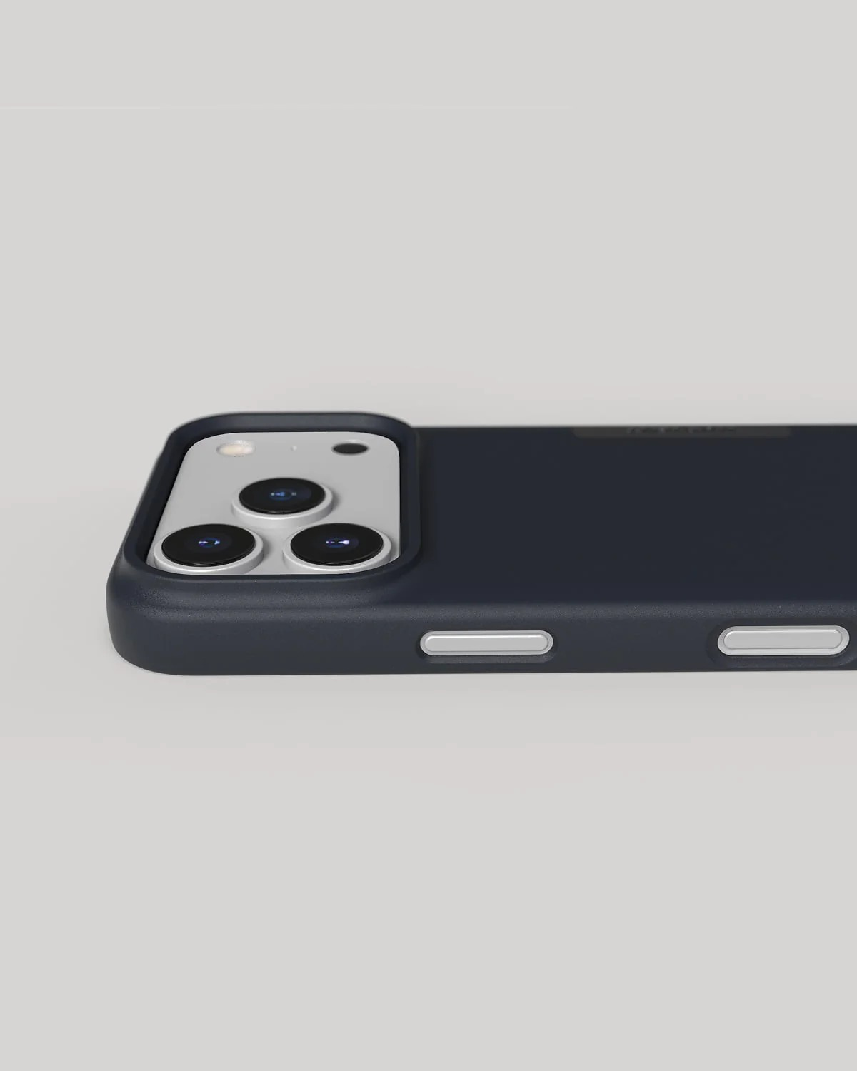 Granatowe etui na telefon z potrójnym modułem aparatu na jasnoszarym tle.