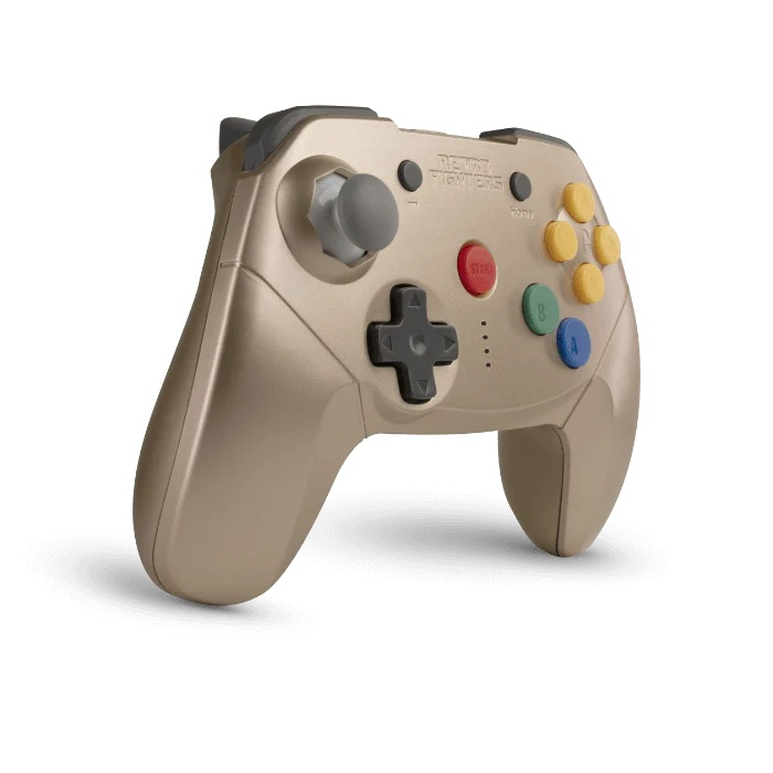 Złoty kontroler z szarymi joystickami, czerwonym przyciskiem start i kolorowymi przyciskami.