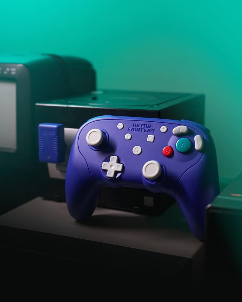 Fioletowy kontroler retro z niebieskim adapterem karty pamięci na ciemnej powierzchni. Konsole do gier w tle.