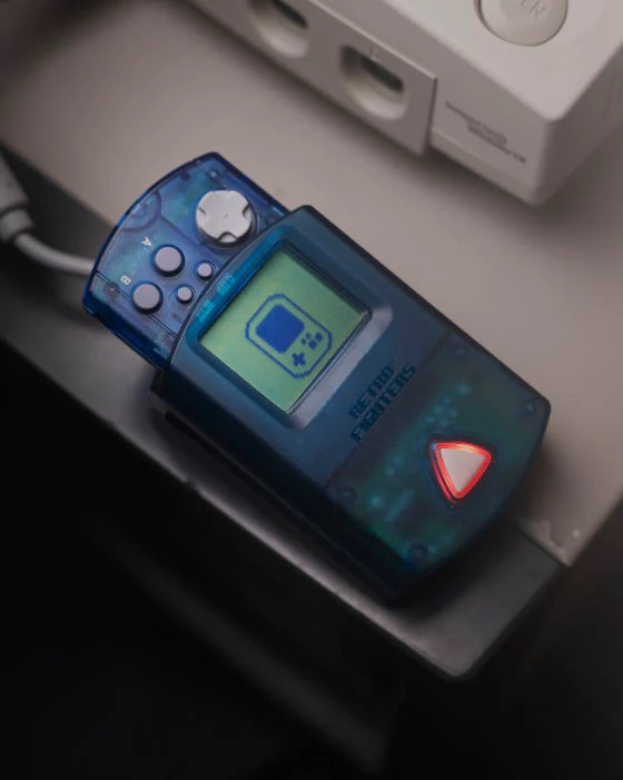 Un controller portatile blu con schermo accanto a una console bianca.