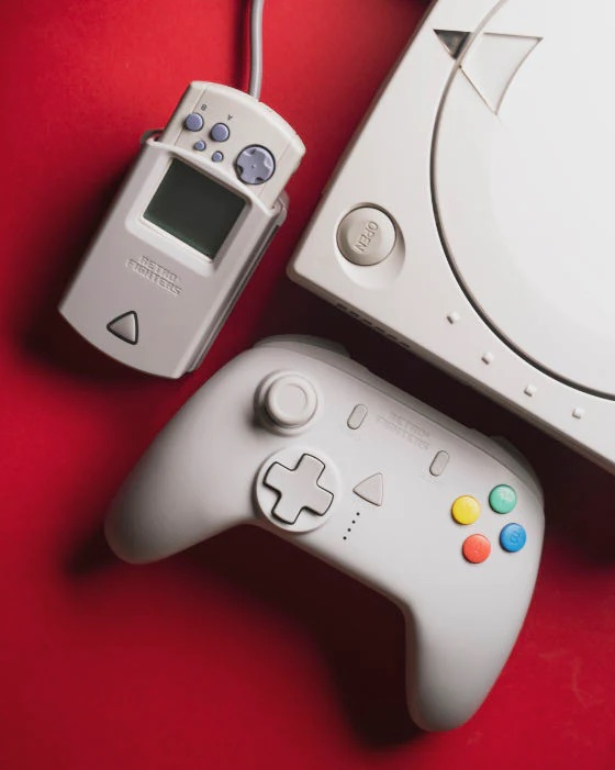 Controller, portatile e console da gioco retrò bianchi su sfondo rosso.