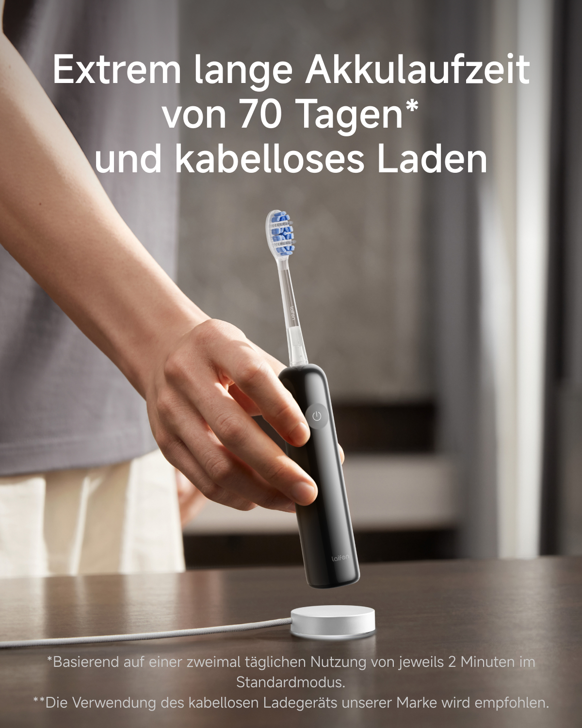 Hand hält schwarze Zahnbürste mit blauem Bürstenkopf über Ladestation.