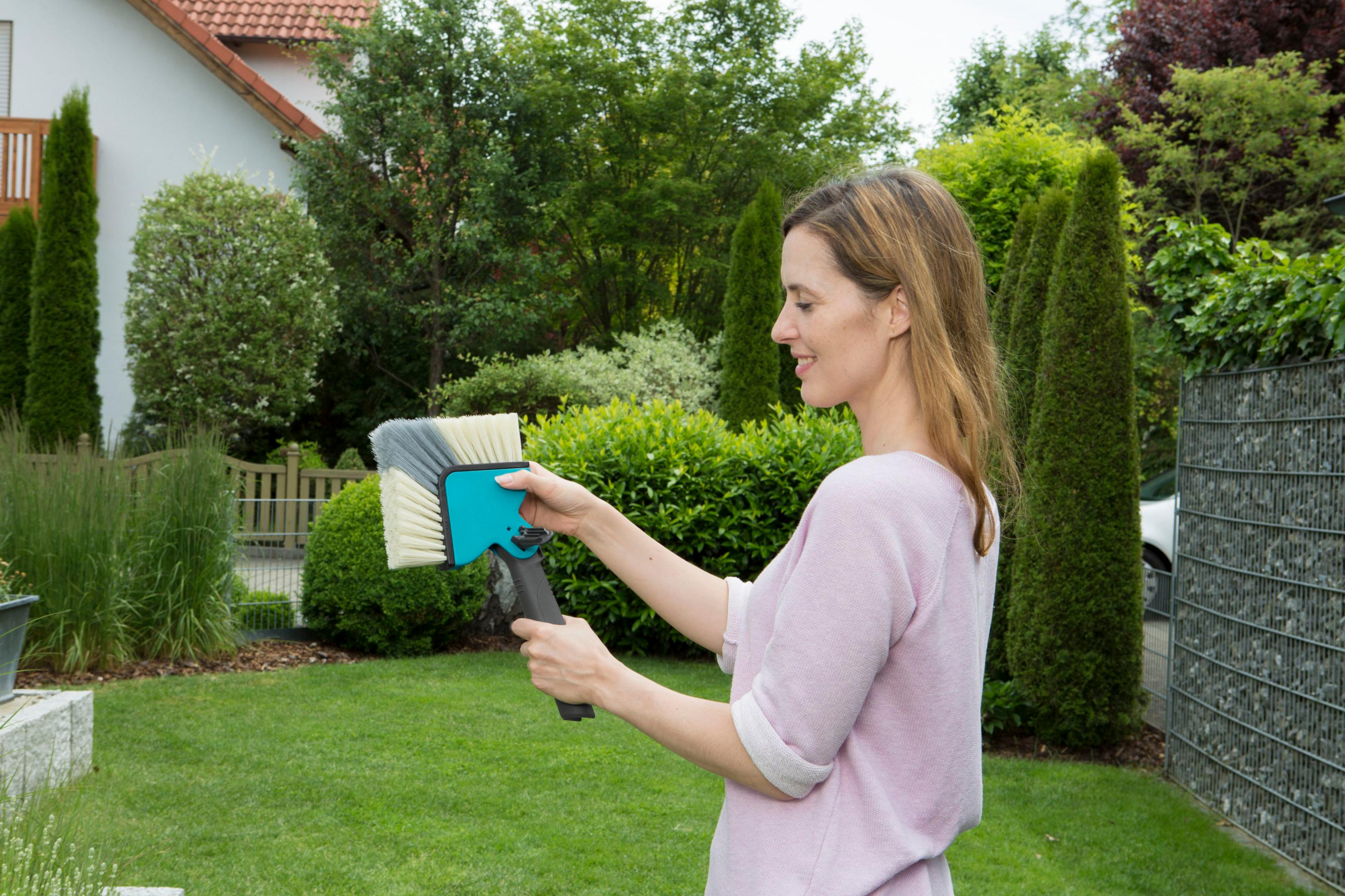 Eine Frau mit einem Bürstenkopf in einem Garten.