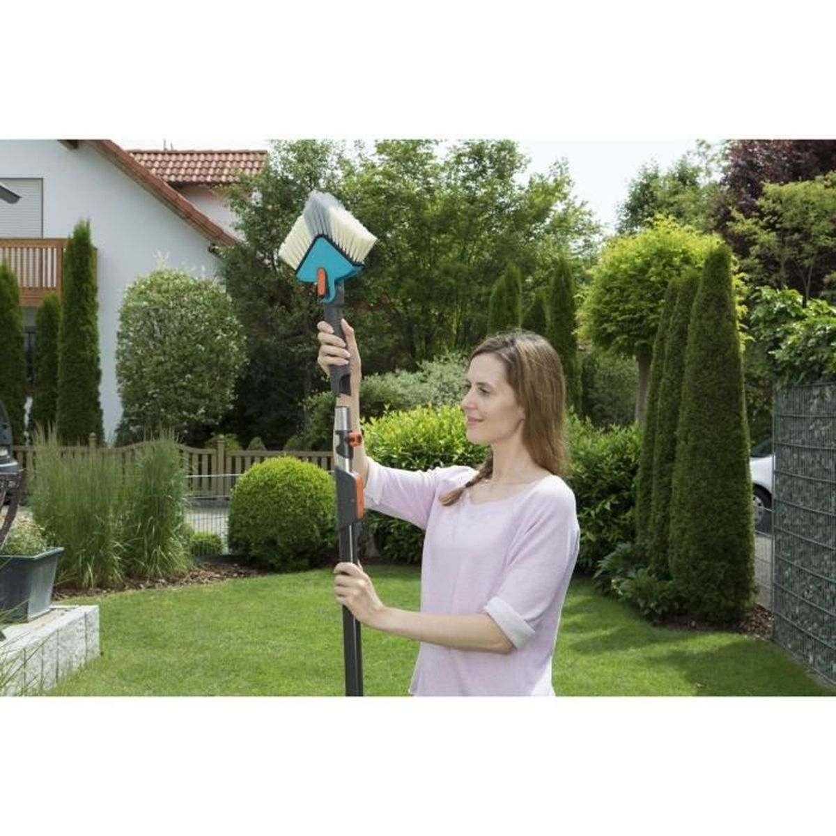 Eine Frau im Garten hält einen Teleskop-Waschbürstenaufsatz.