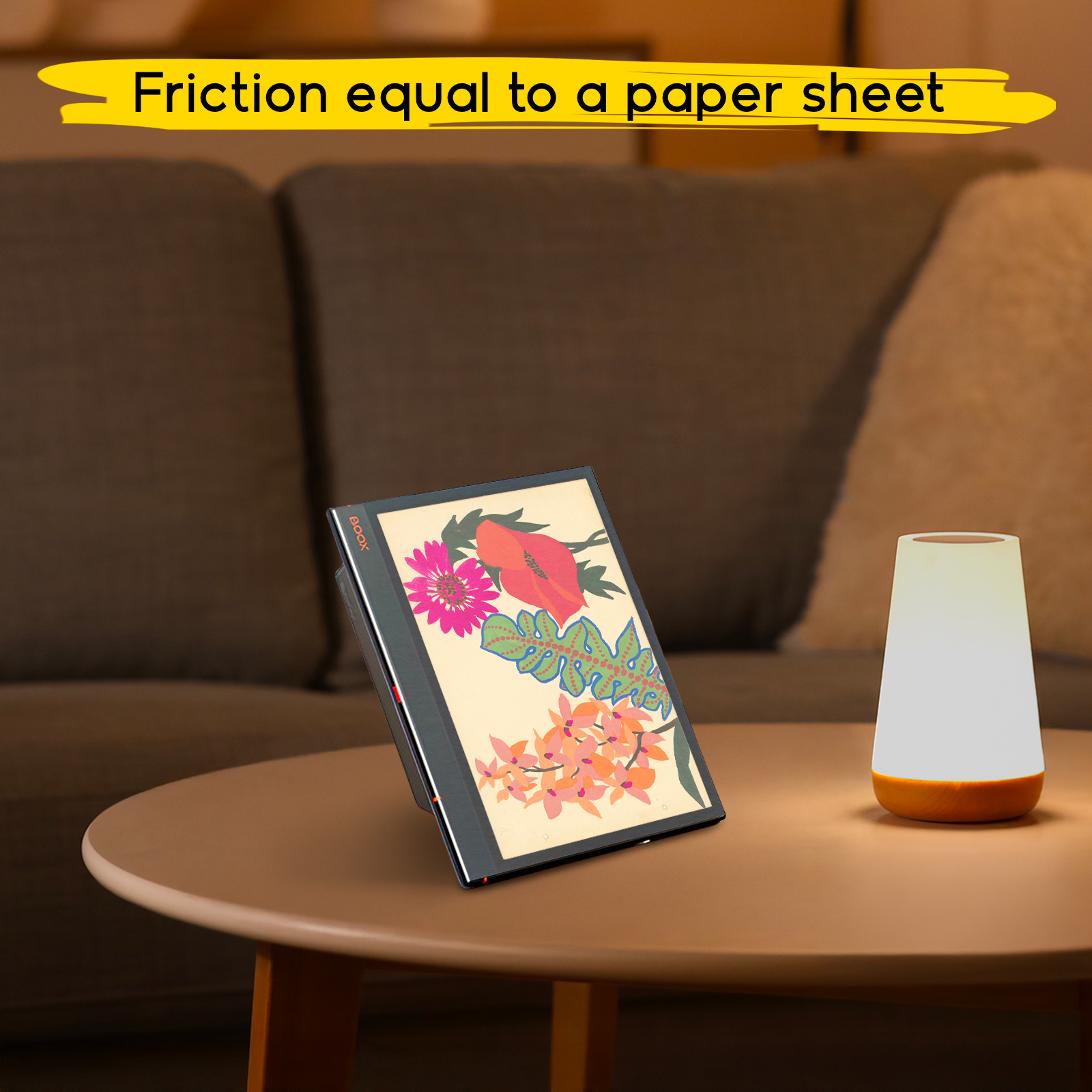 Una tablet con arte floral descansa en una mesa junto a una lámpara, con un sofá detrás.