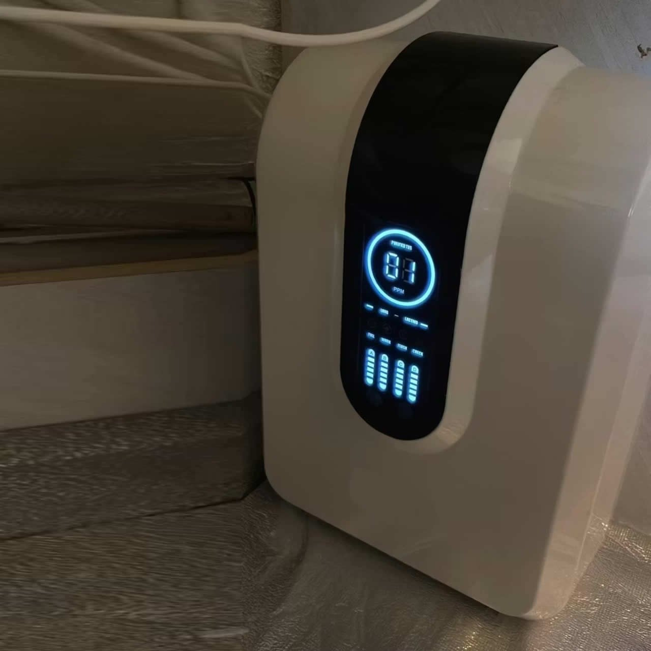 Siyah bantlı ve mavi ışıklı ekrana sahip beyaz cihaz 84 PPM gösteriyor.